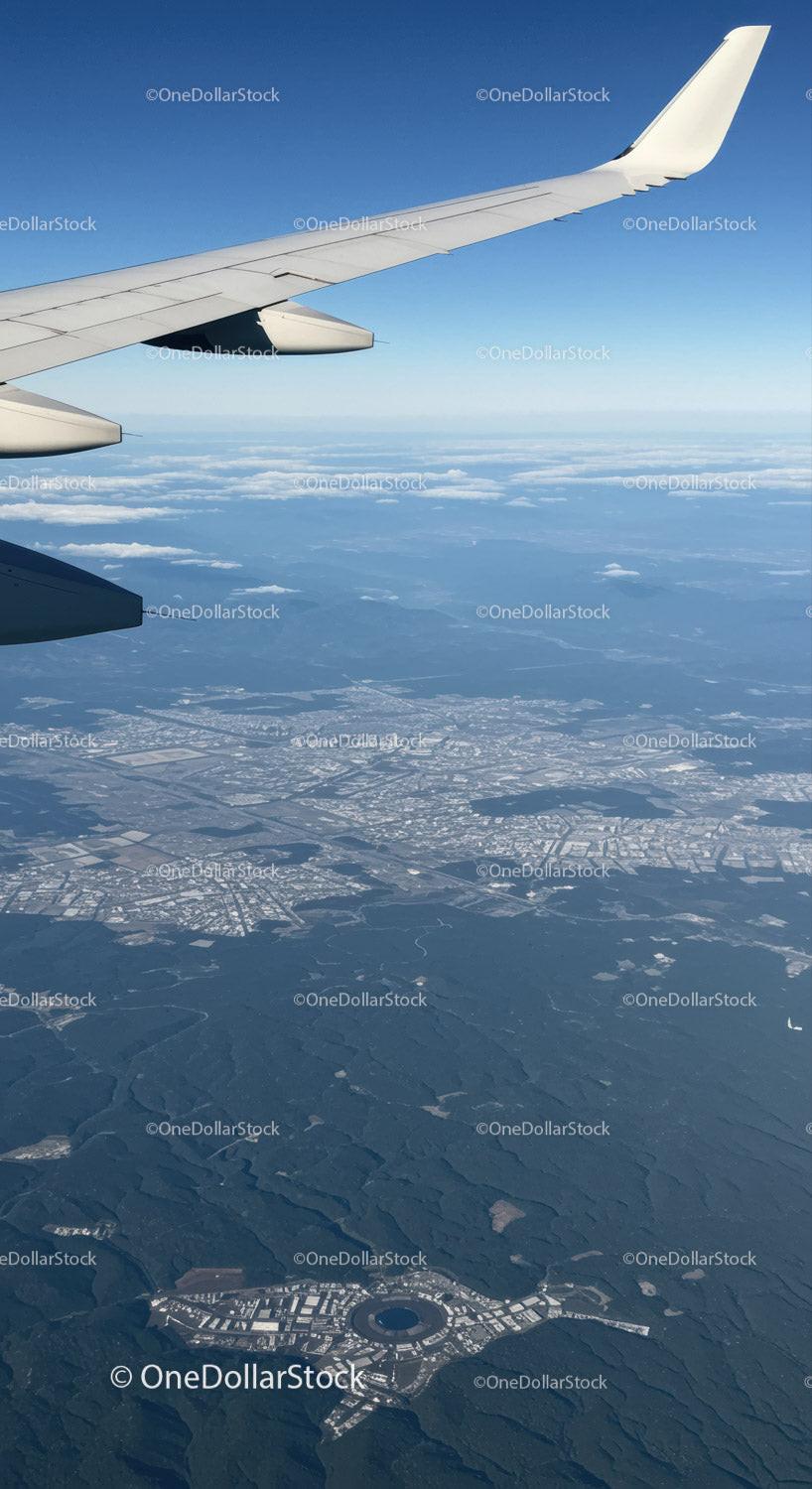 Aerial View of Cityscape with Airplane Wing Over Urban Landscape