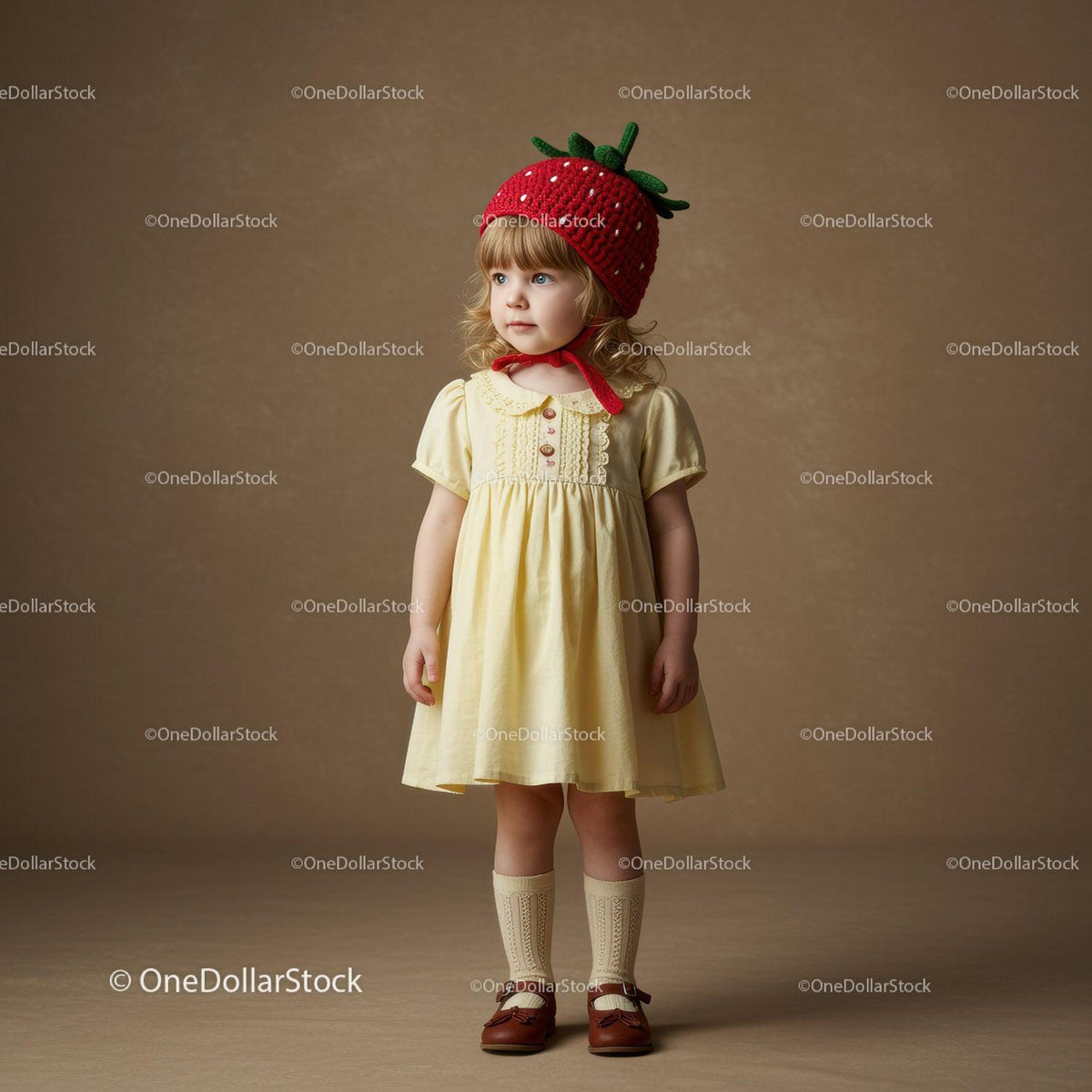 Little girl wearing strawberry hat and yellow dress
