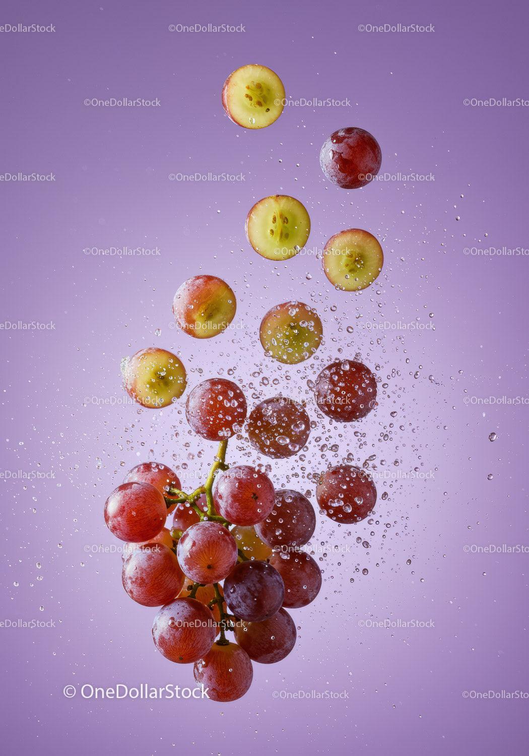 Fresh red grapes bursting with water droplets on purple