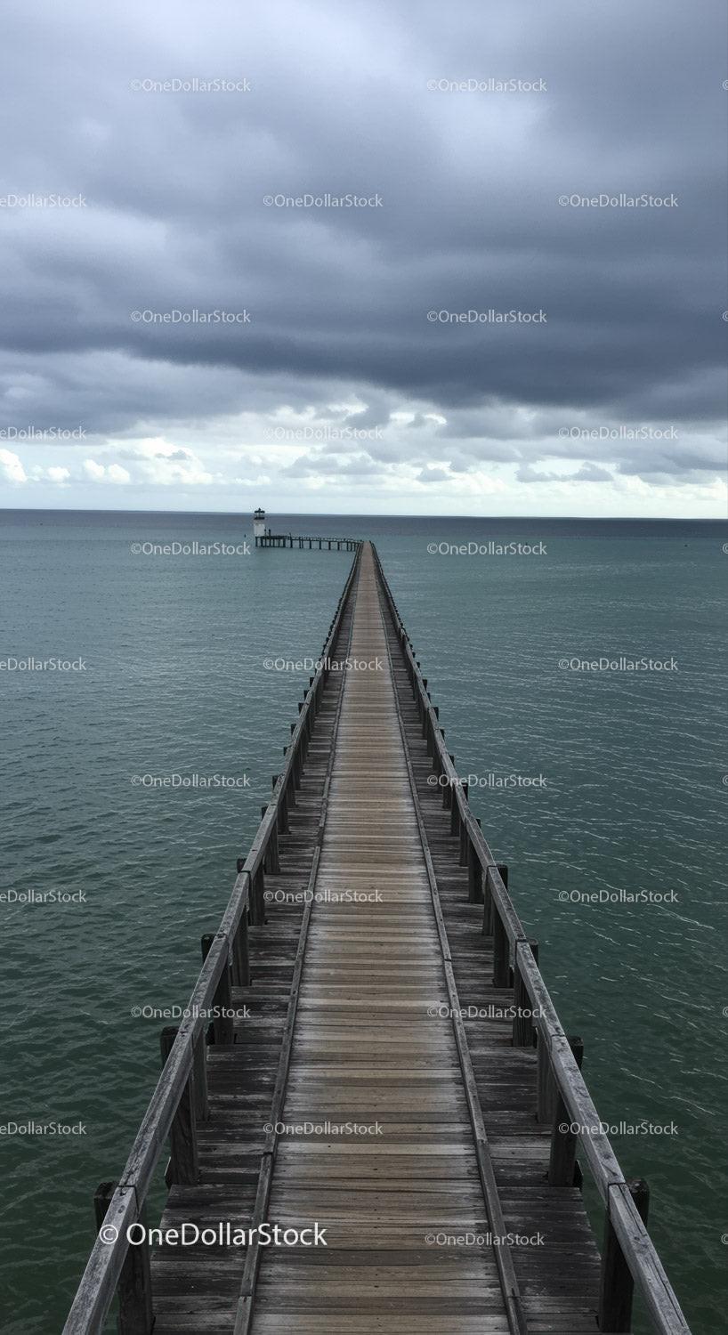 Wooden Pier Leading to Lighthouse Under Dramatic Cloudy Sky
