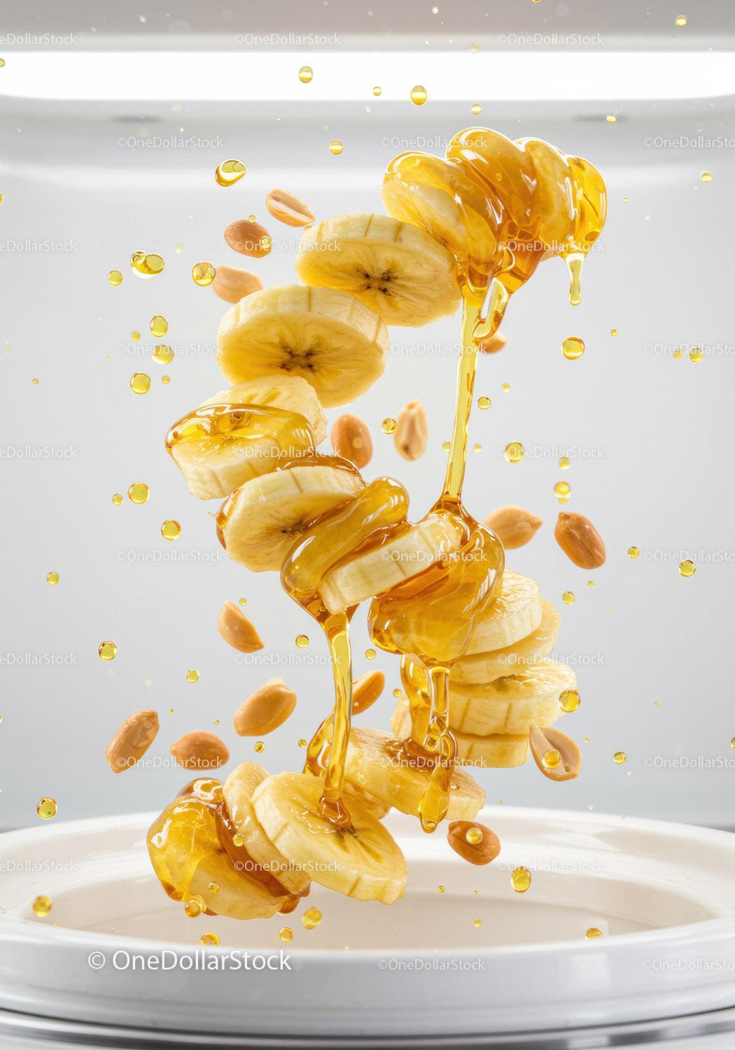 Sliced banana with honey drizzle and peanuts falling