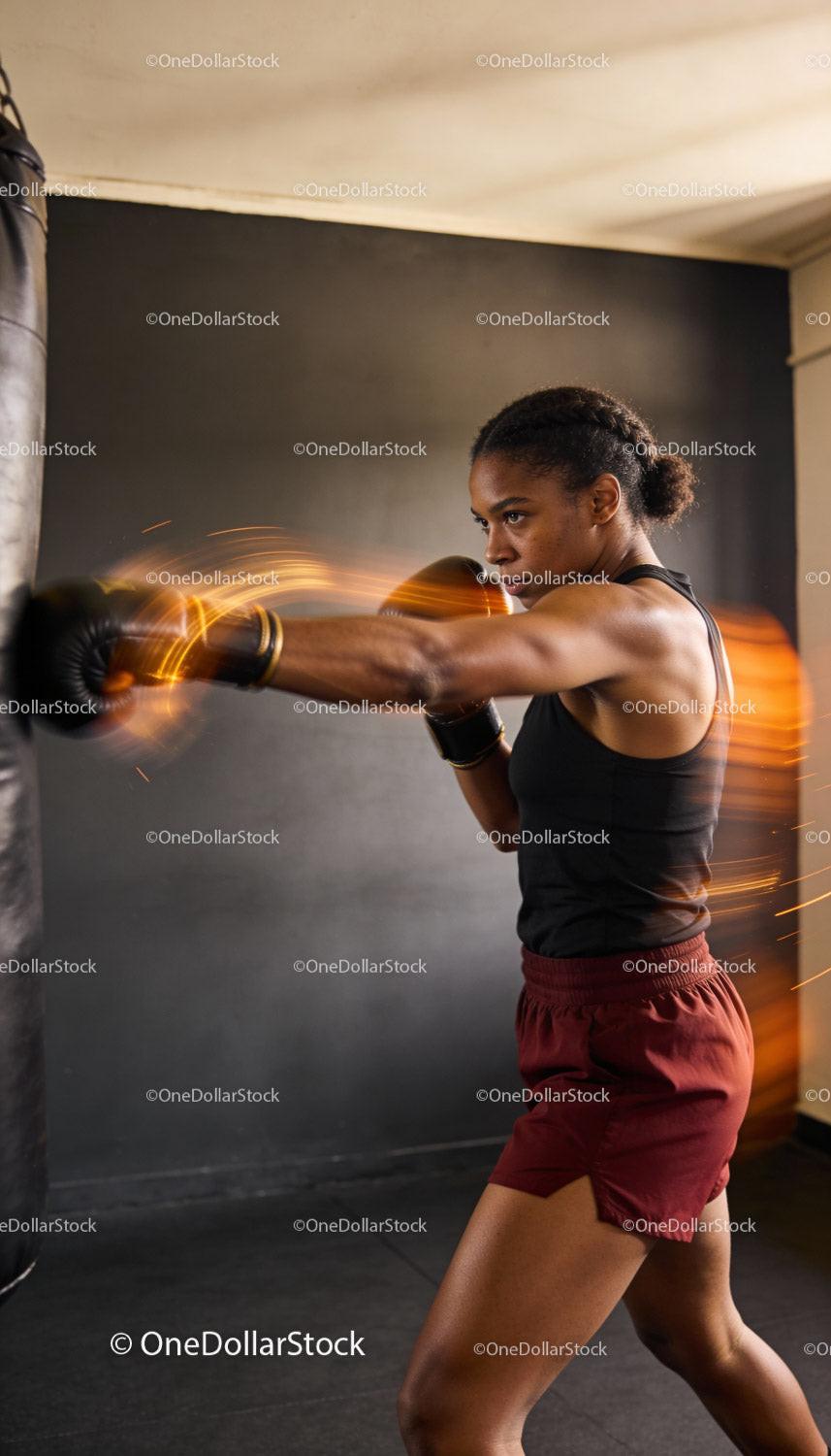 Focused female boxer training intensely with punching bag