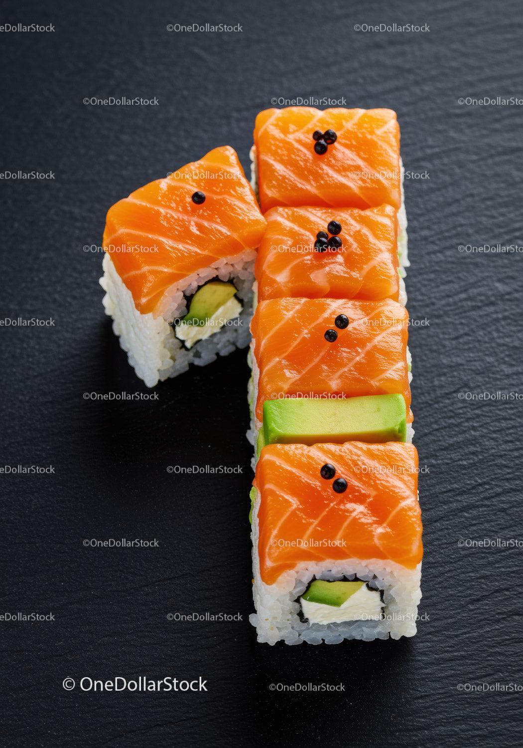 Fresh salmon sushi rolls with avocado on black plate