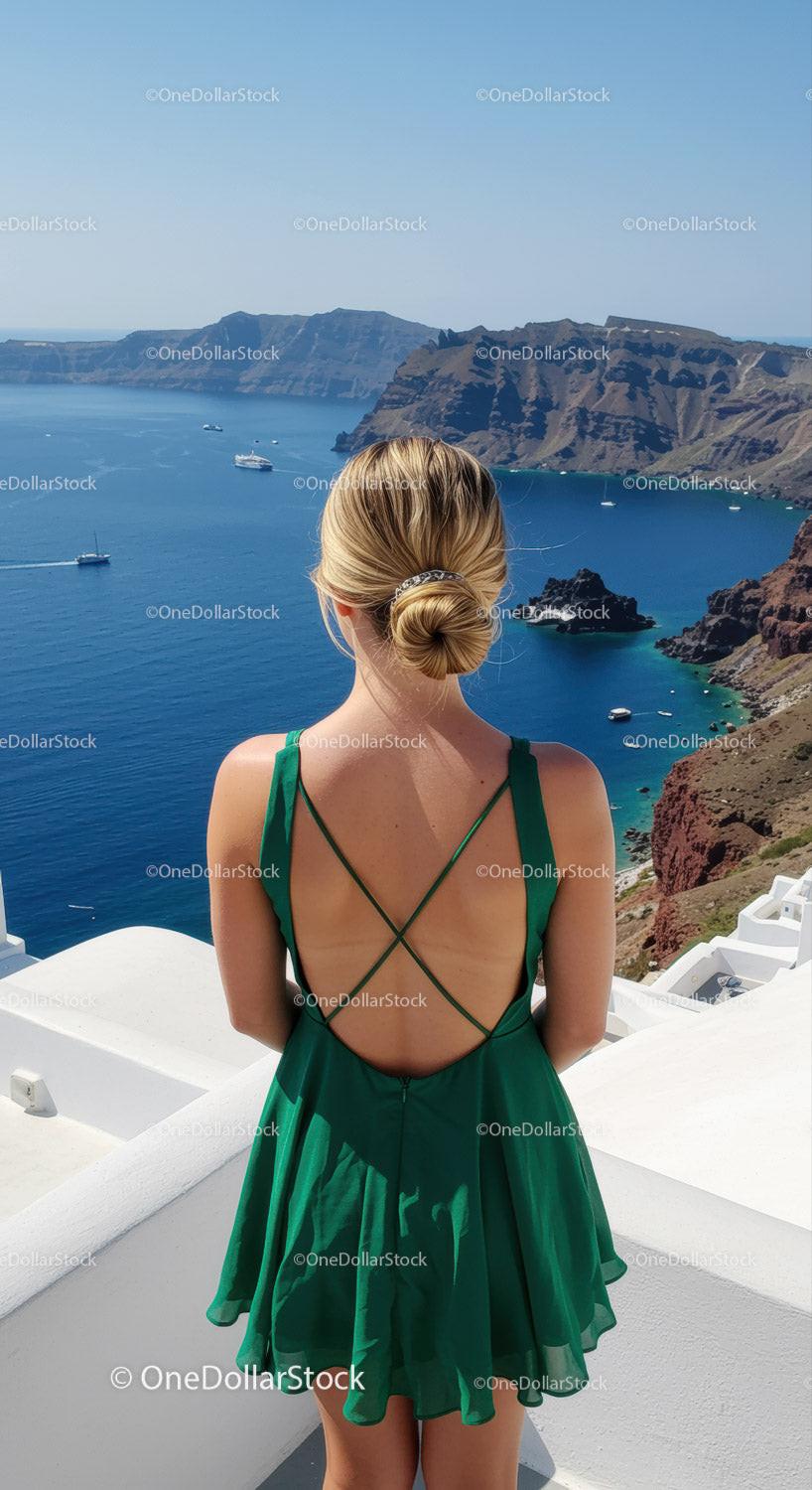 Woman in green dress overlooking serene sea cliffs