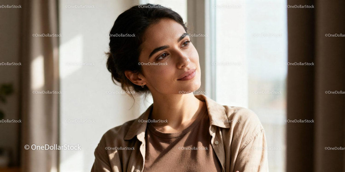 Thoughtful young woman gazing out bright window