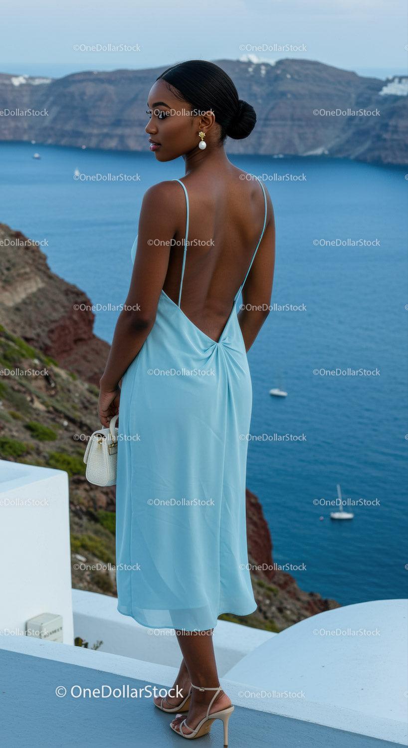 Elegant woman in blue dress overlooking serene ocean view