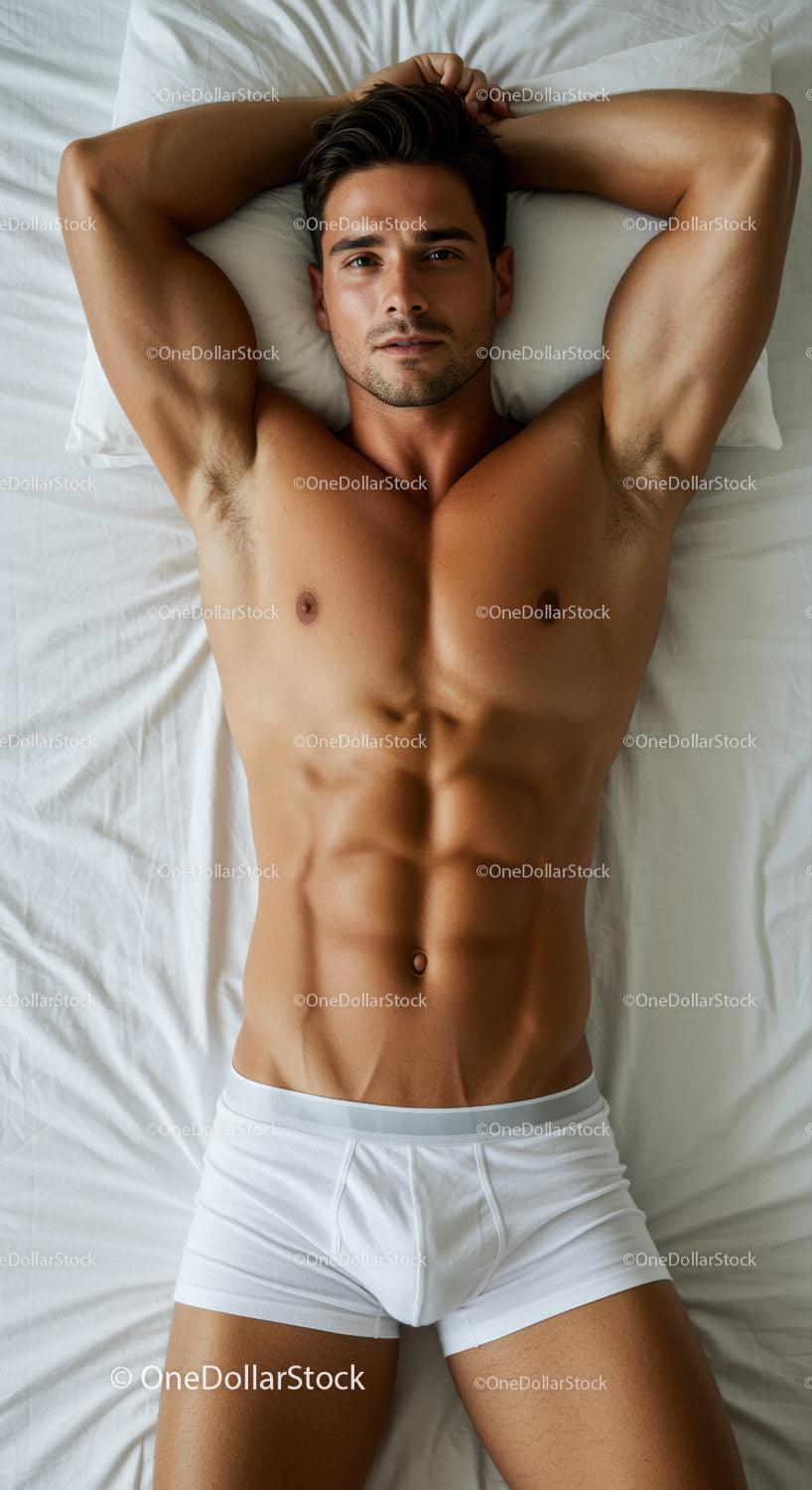 Fit man resting on bed with hands behind head