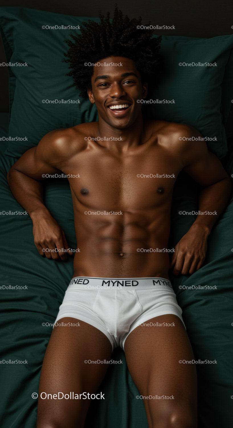 Smiling young man lying on dark green bed sheets