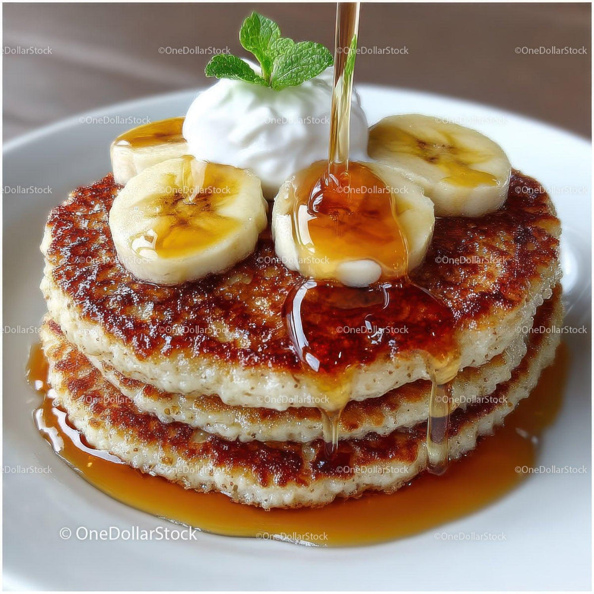 Banana Pancakes with Syrup and Banana Slices on White Plate