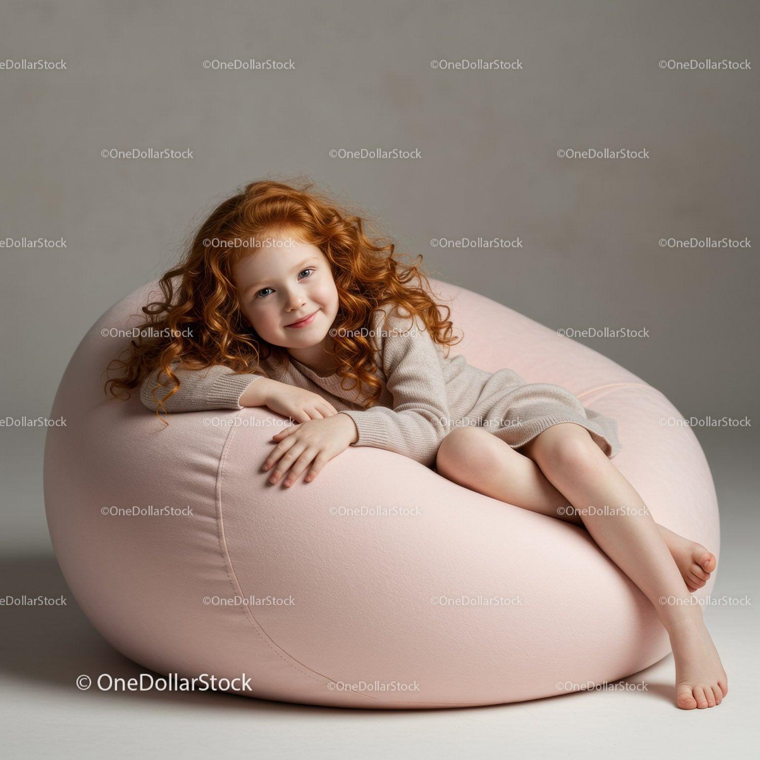 Smiling redhead girl relaxing on soft pink bean bag