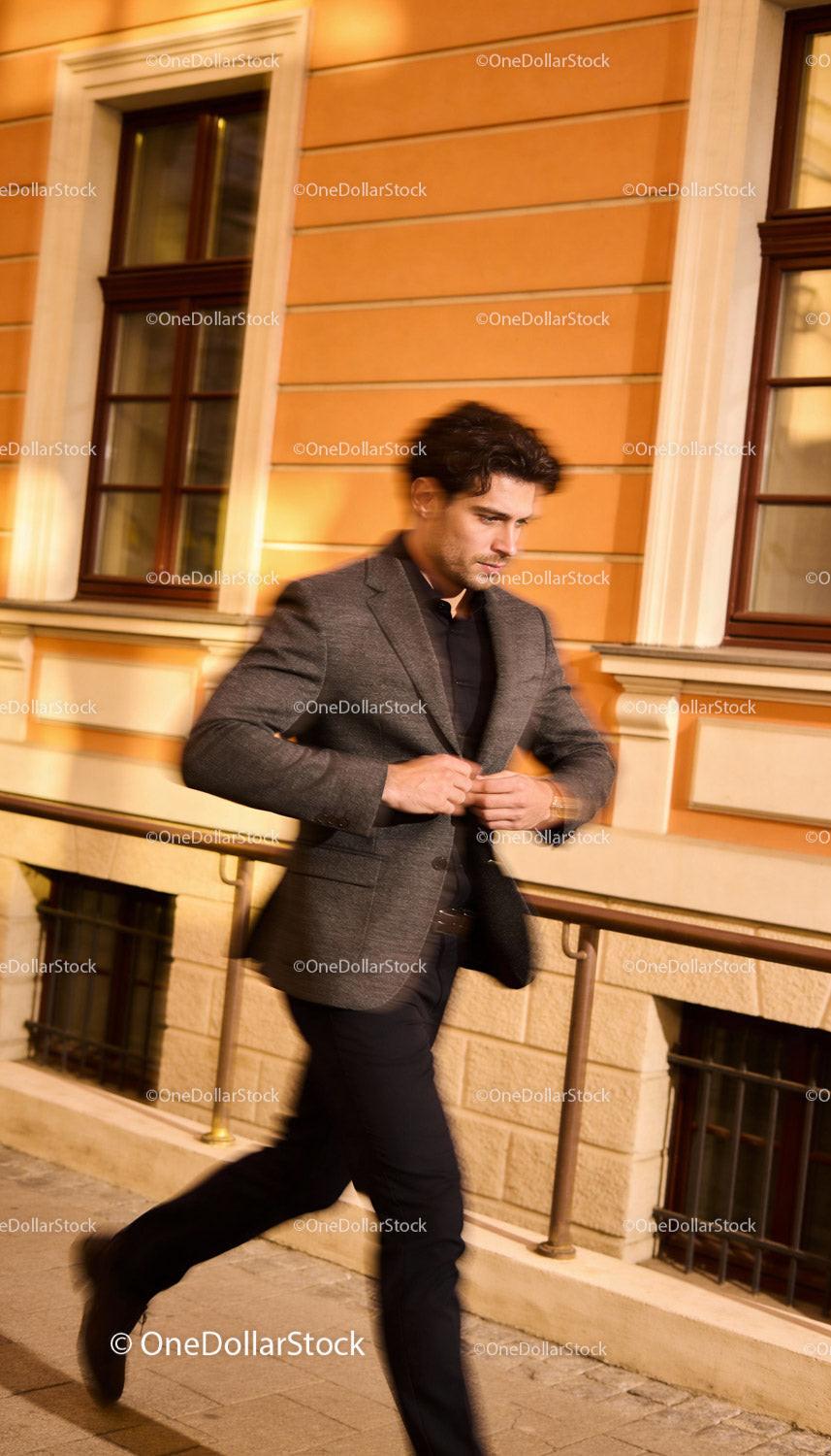 Stylish man buttoning blazer on urban street at night