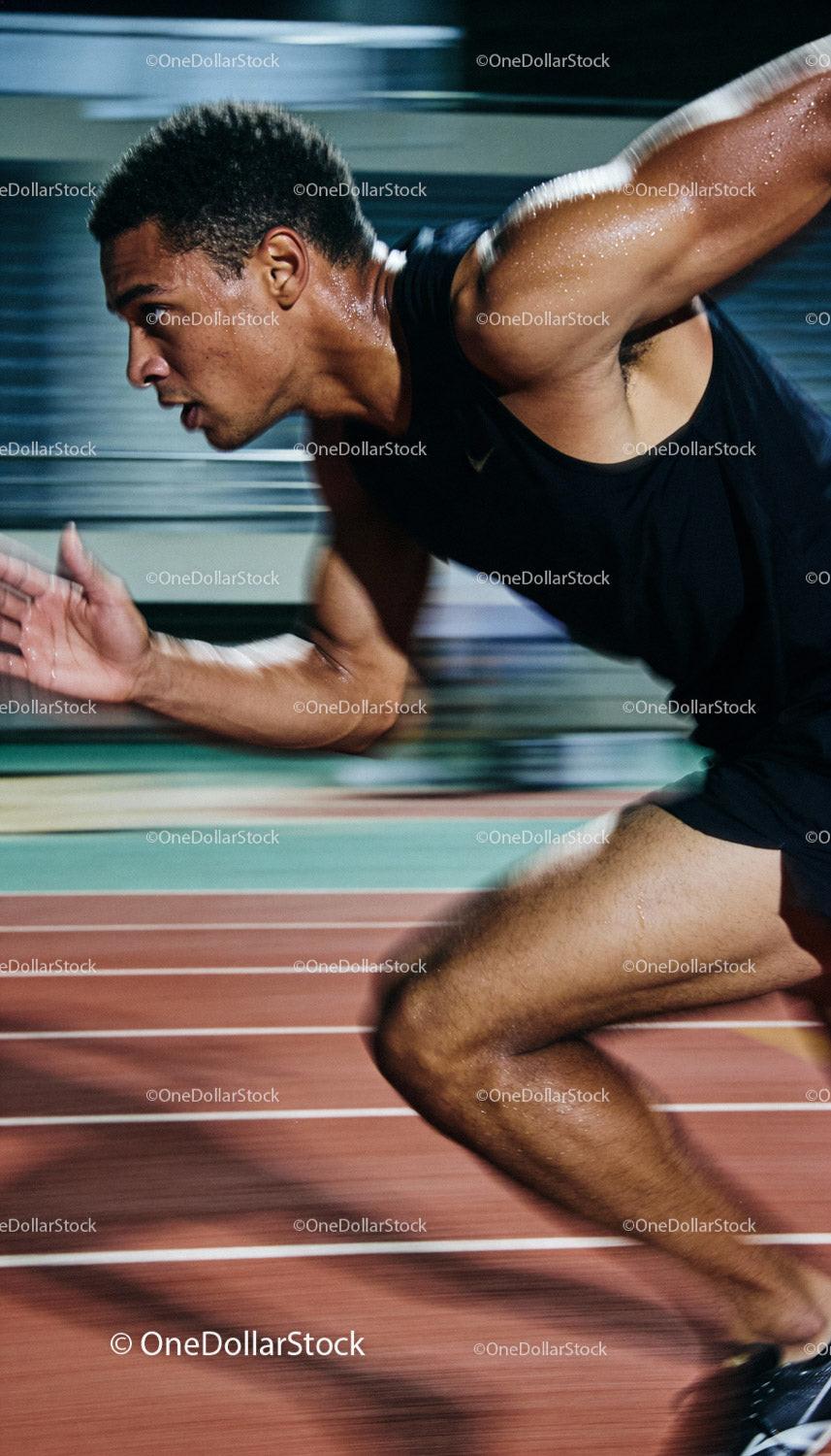 Focused sprinter launching off the starting blocks