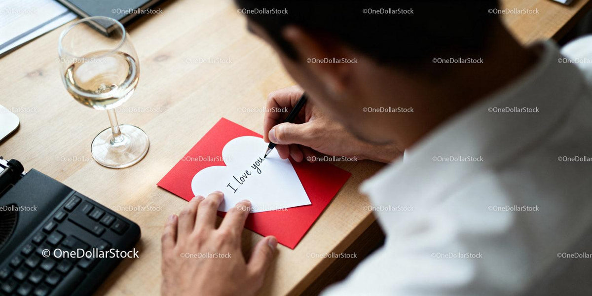Man writing romantic message on heart-shaped card