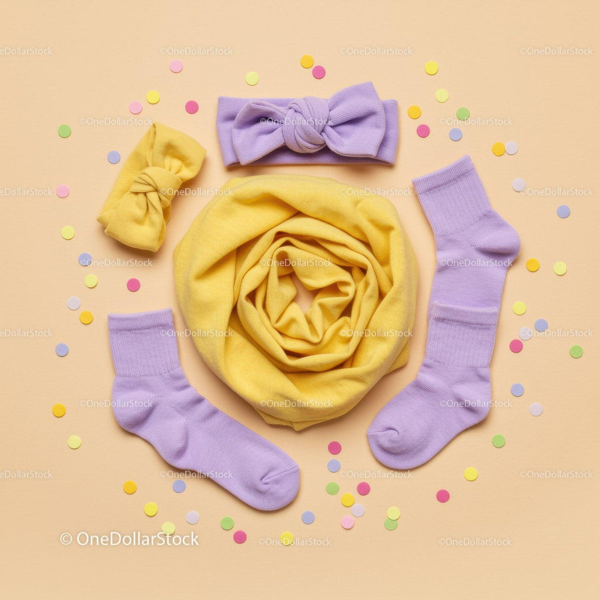 Pastel baby accessories with confetti on beige background
