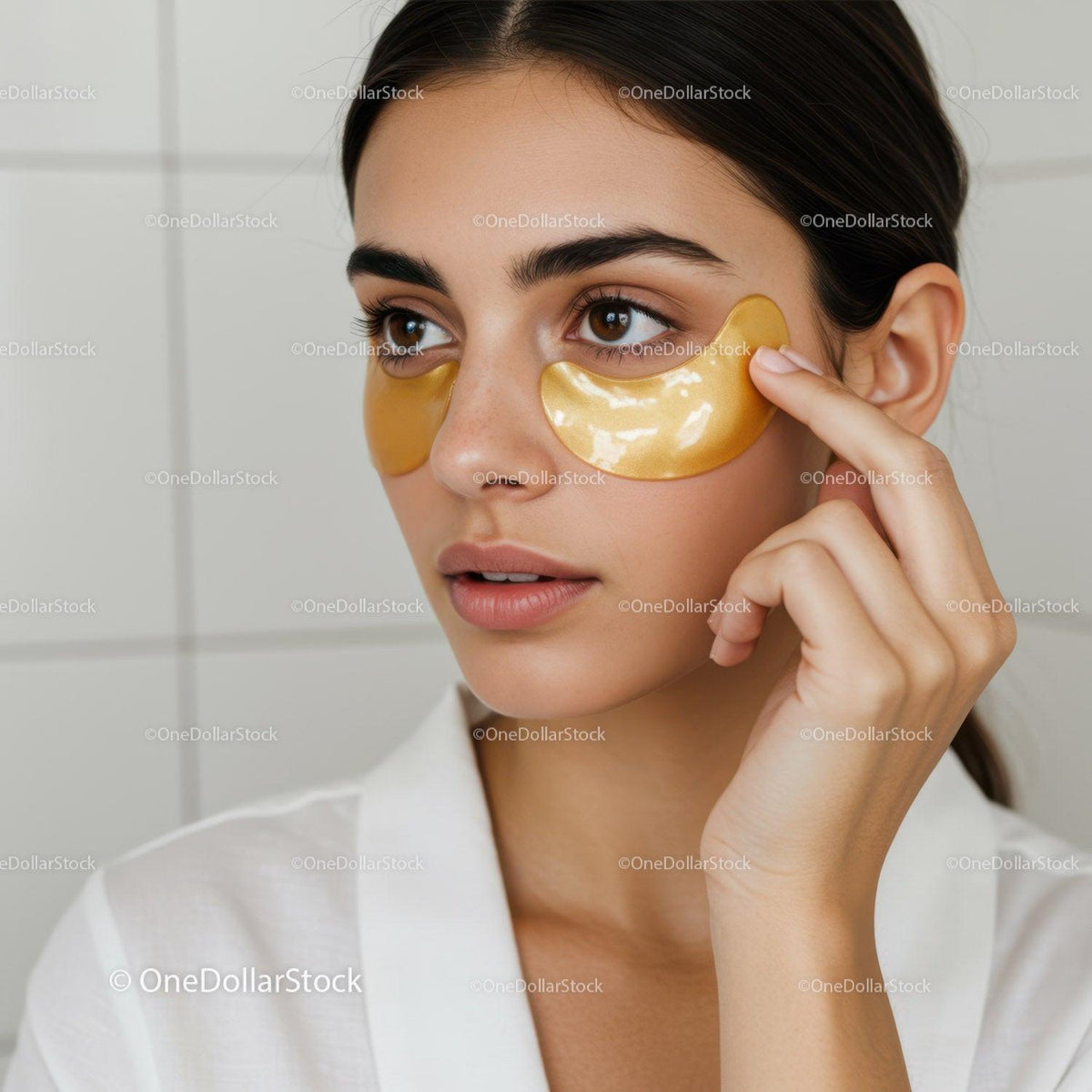 Young Woman in White Shirt Applying Gold Eye Patches for Skincare