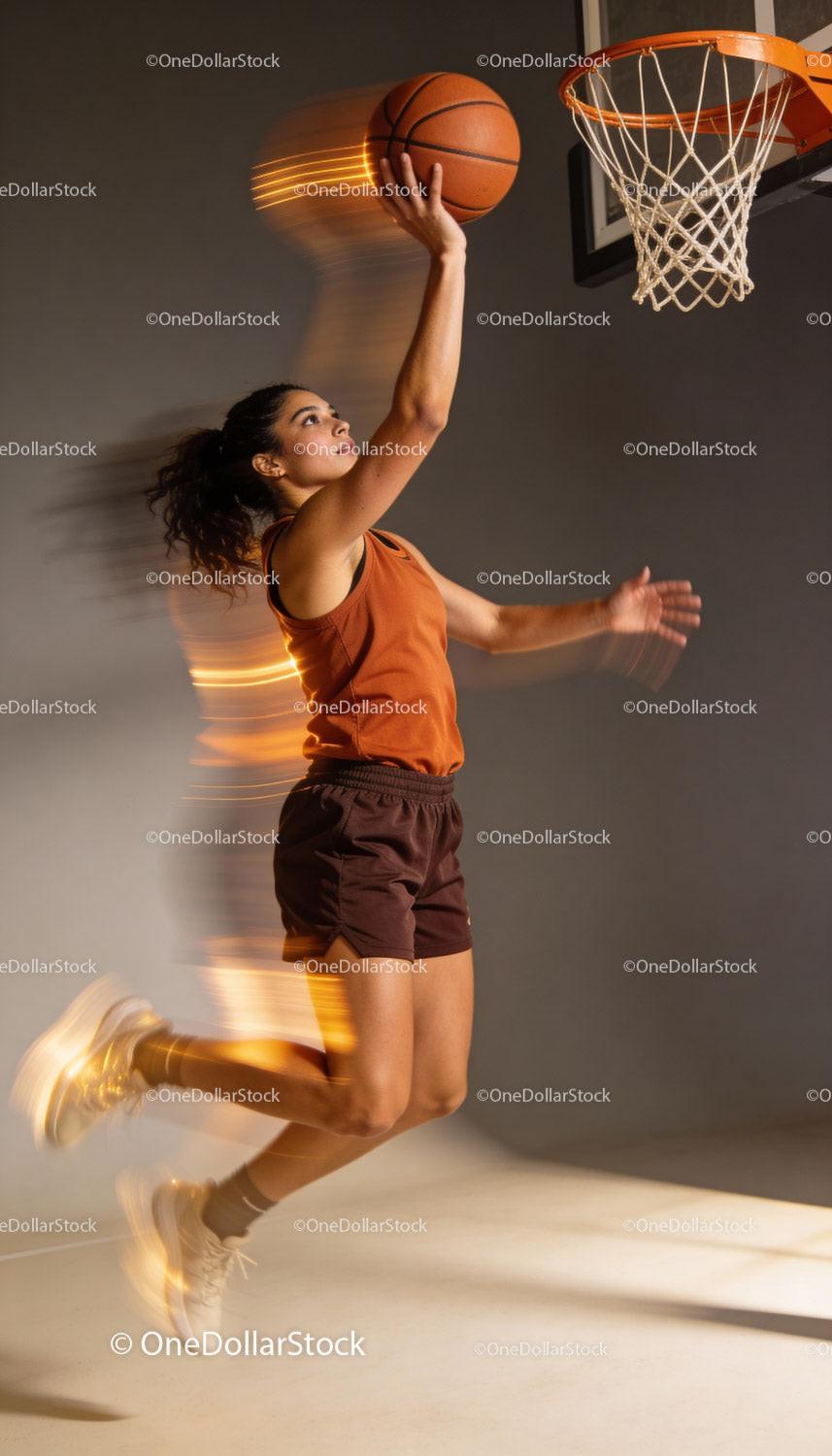 Female basketball player jumping for layup shot indoors