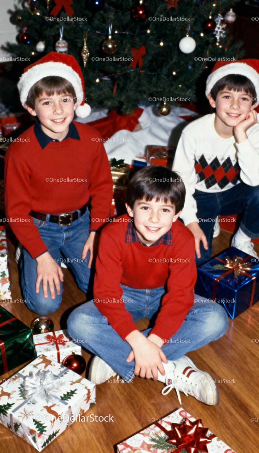 Three Smiling Boys in Holiday Sweaters by Christmas Tree