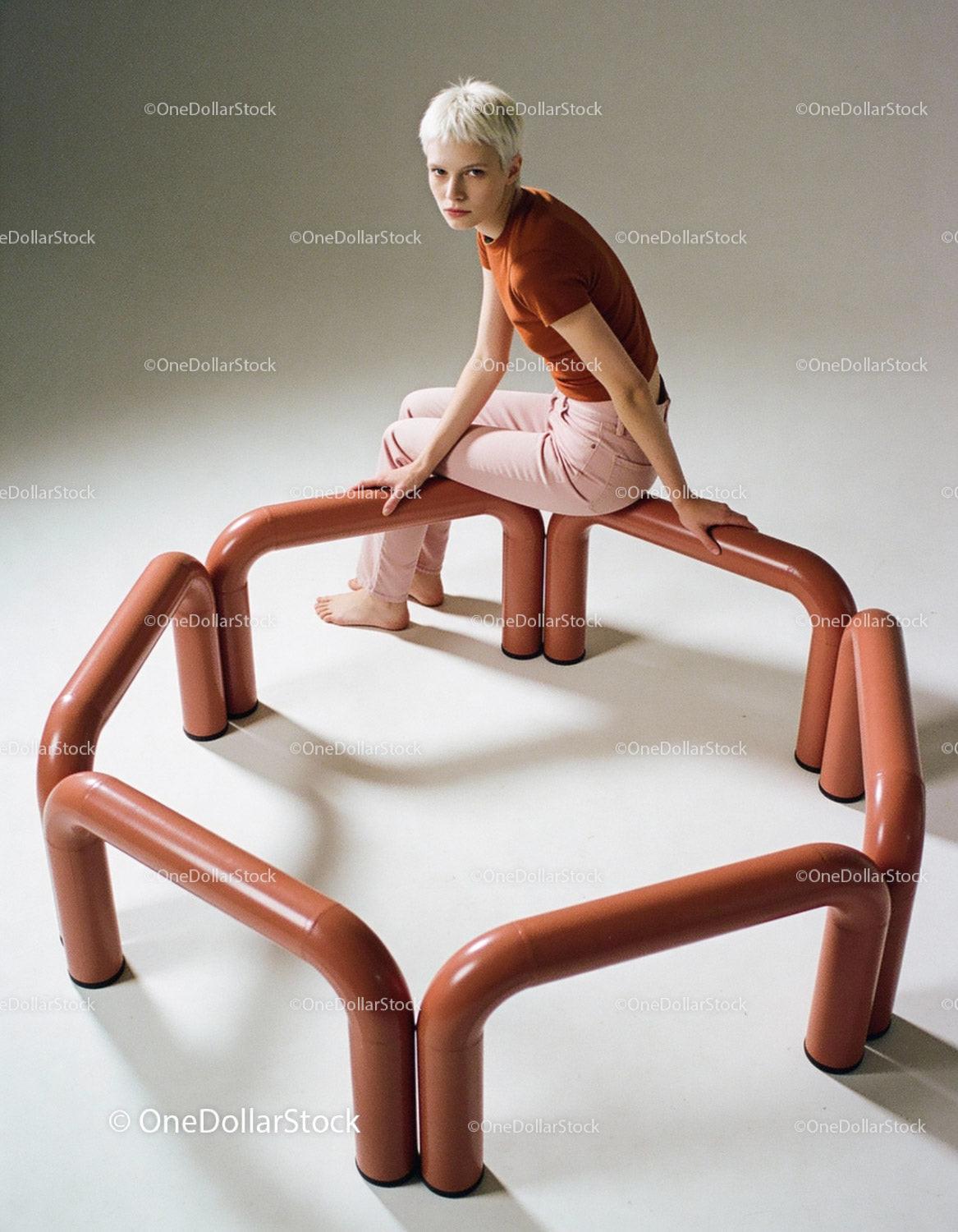 Young woman seated on modern sculptural bench indoors