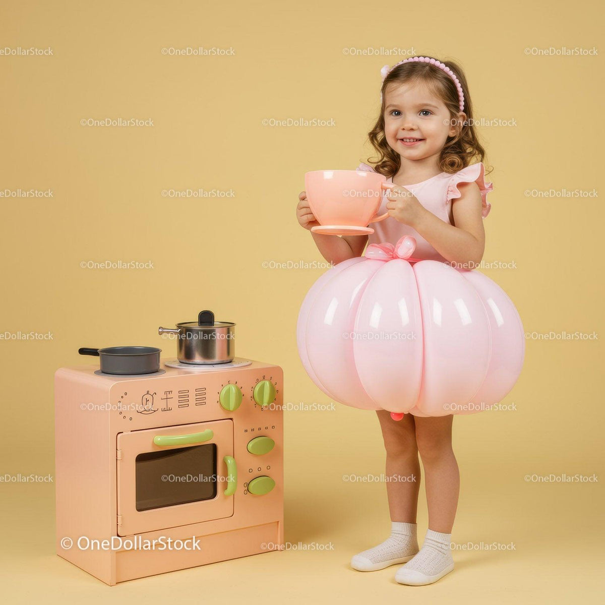 Little girl in balloon dress playing with toy kitchen