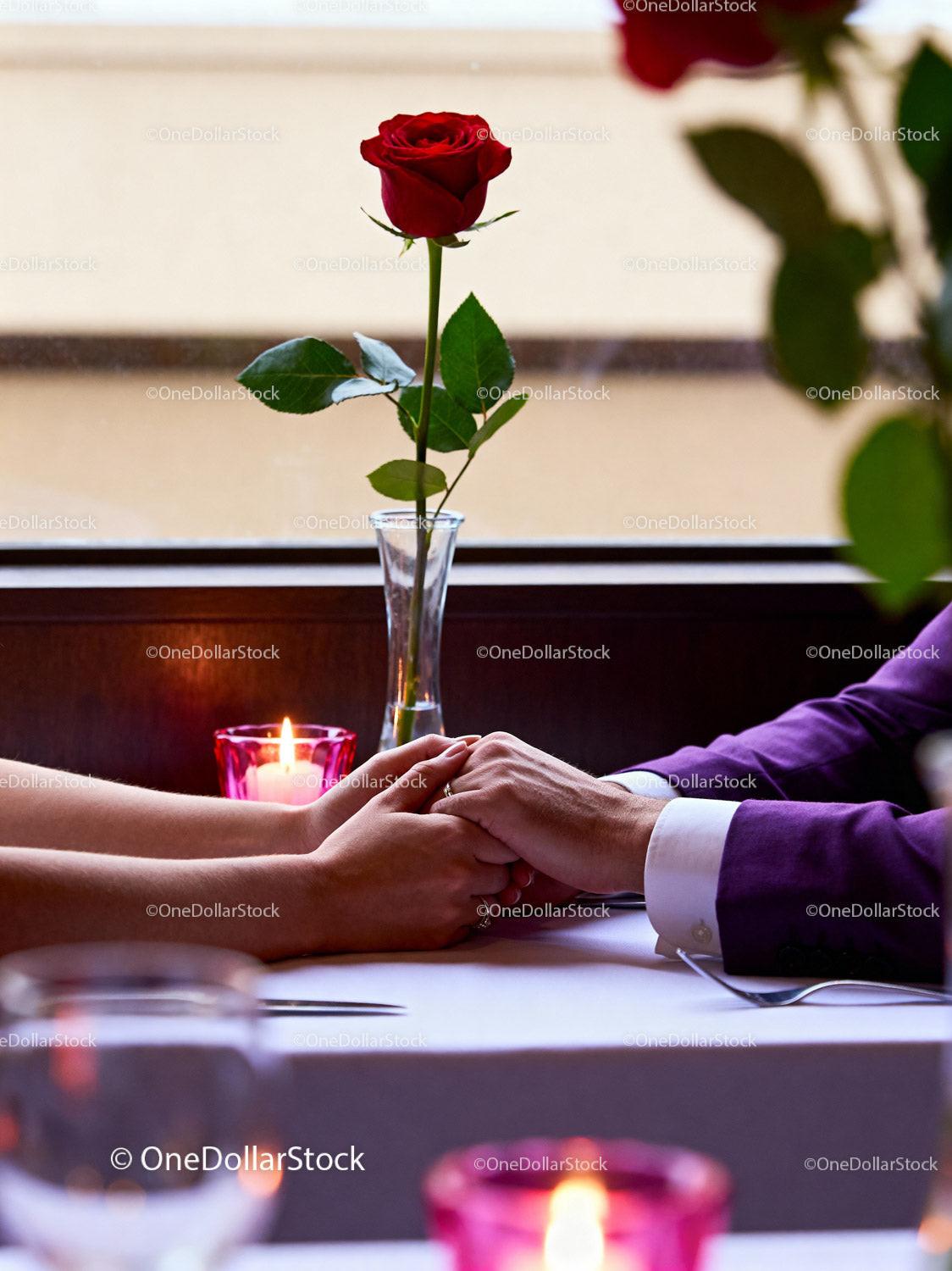 Couple holding hands over a romantic dinner table