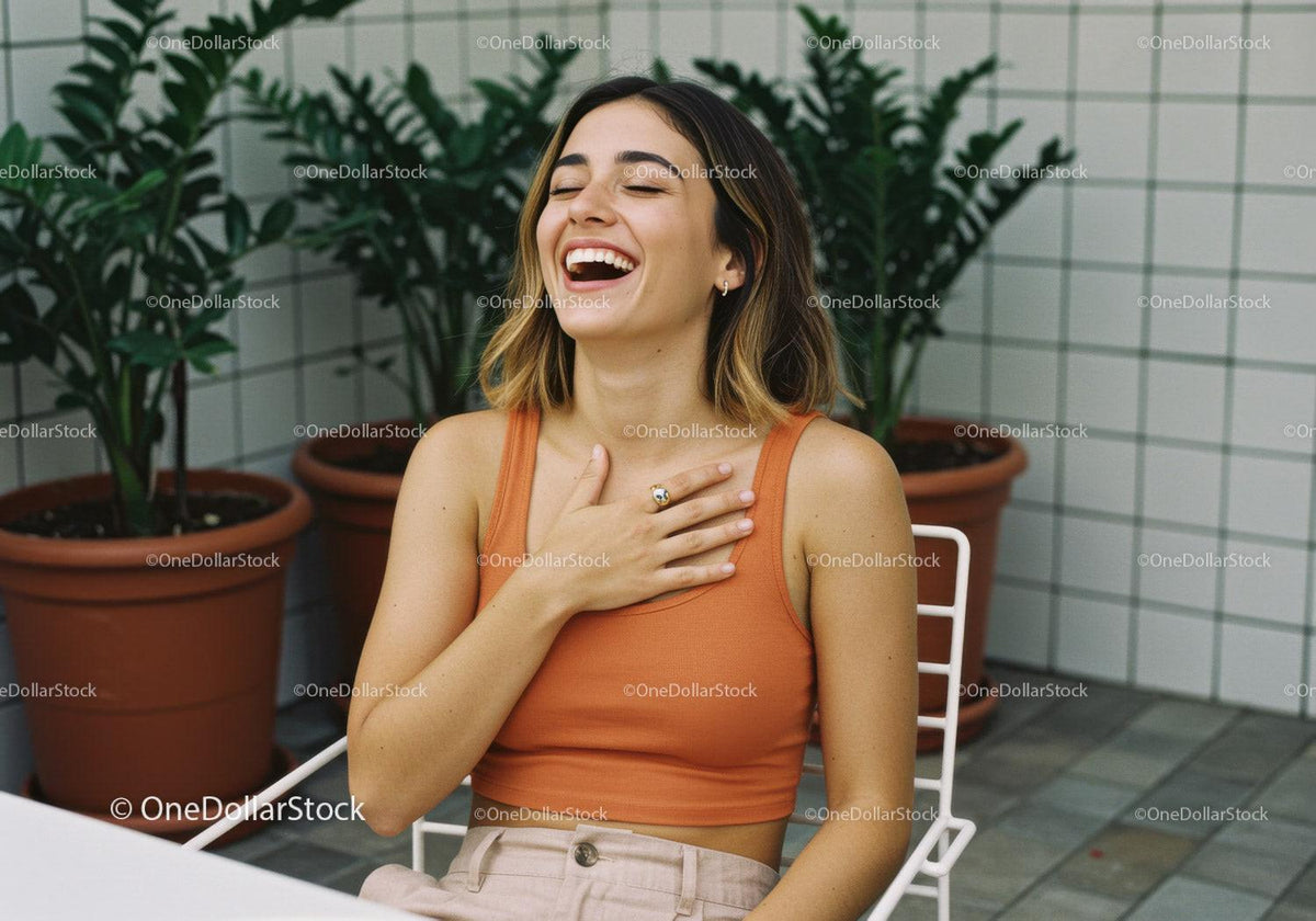 Joyful Young Woman in Orange Top Laughing with Potted Plants in Modern Indoor Garden