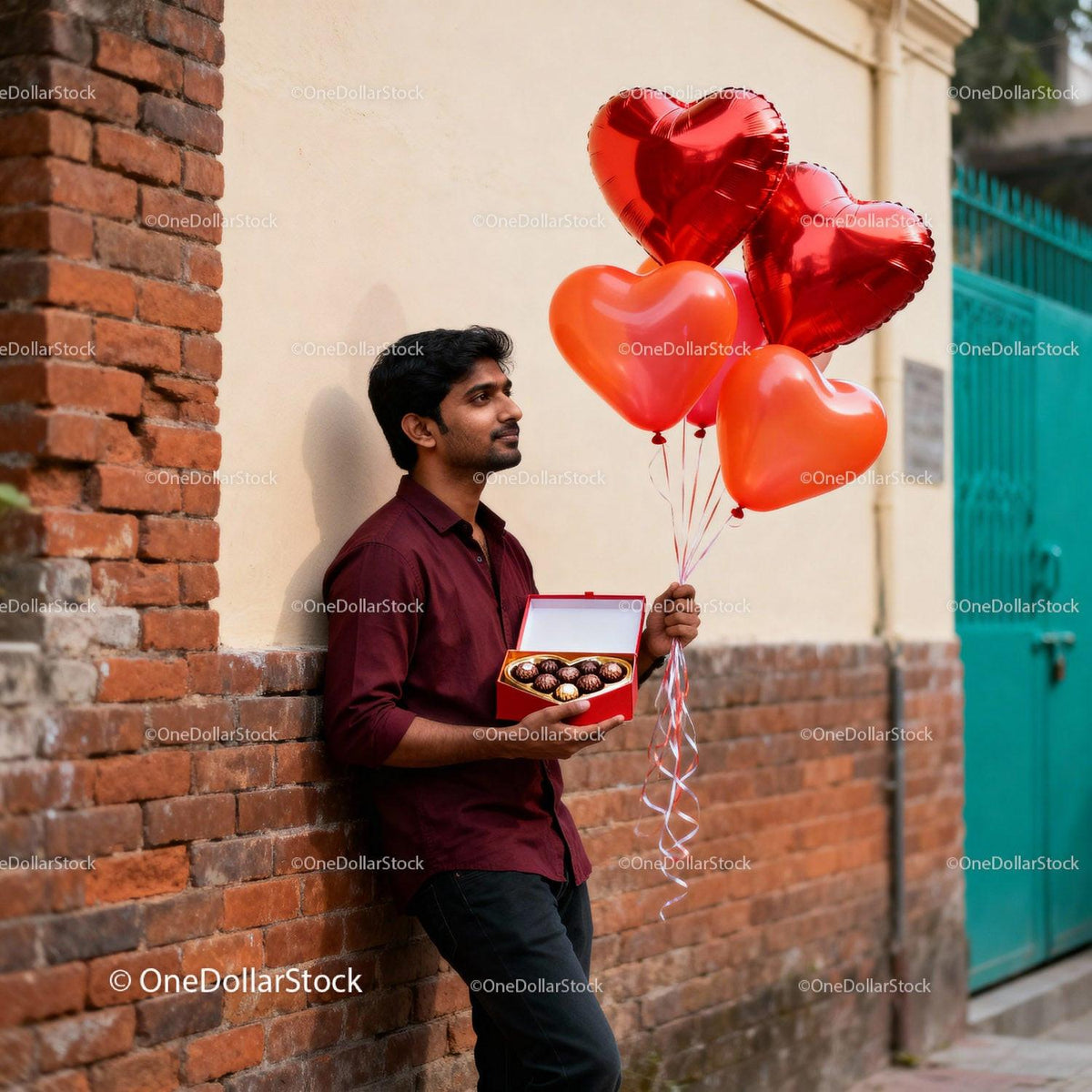 Man holding heart balloons and chocolates outdoors