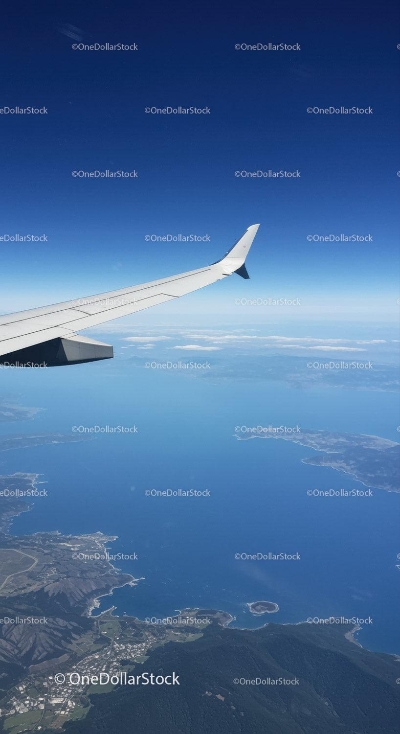 Aerial View of Airplane Wing Over Coast and Mountains