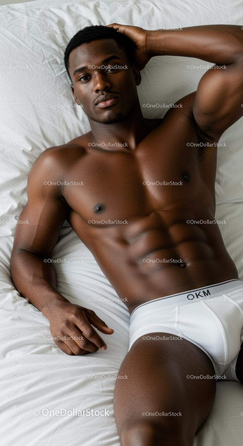 Relaxed fit young man lying on white bed sheets