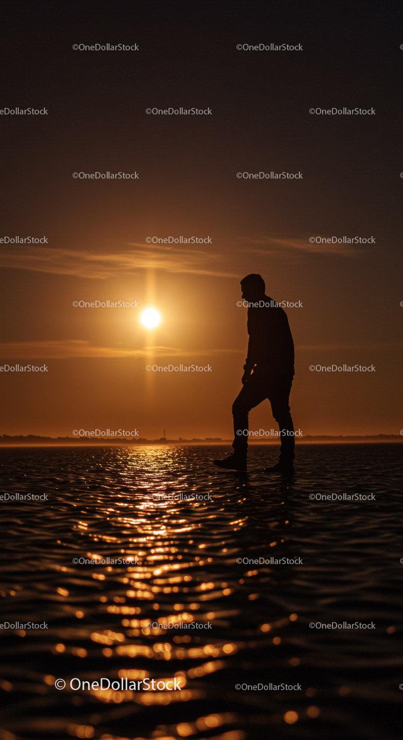 Silhouette of person walking on water at sunset