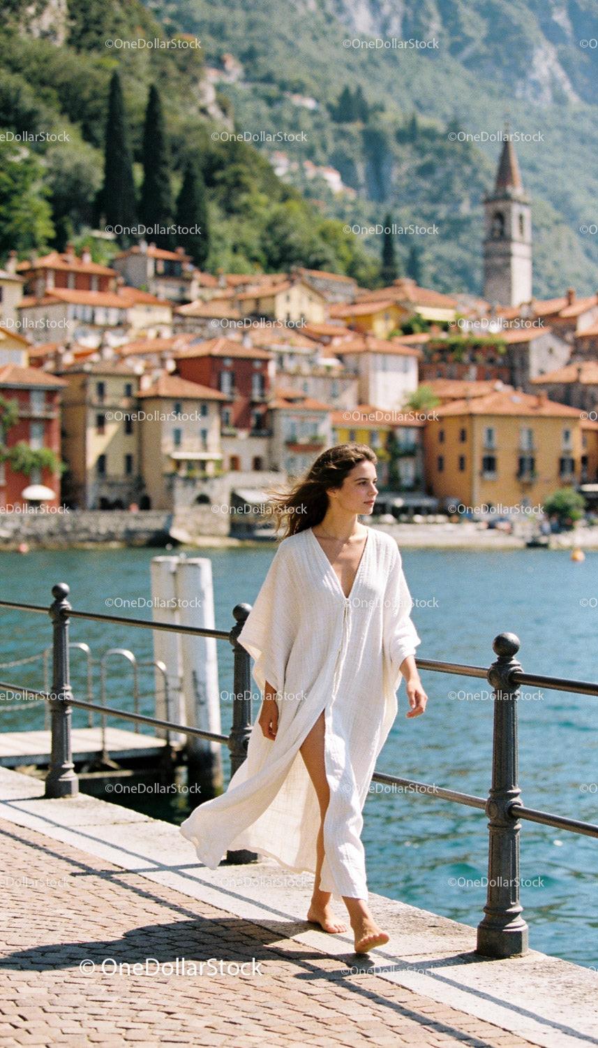 Woman Walking Barefoot in Flowing White Dress by Lake