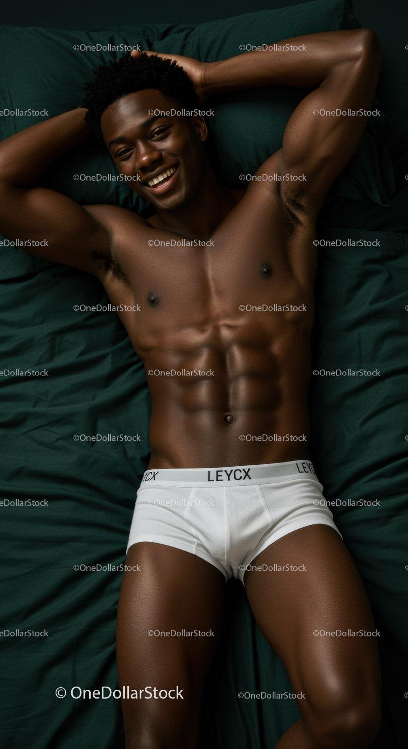 Smiling man relaxing in white underwear on dark bed