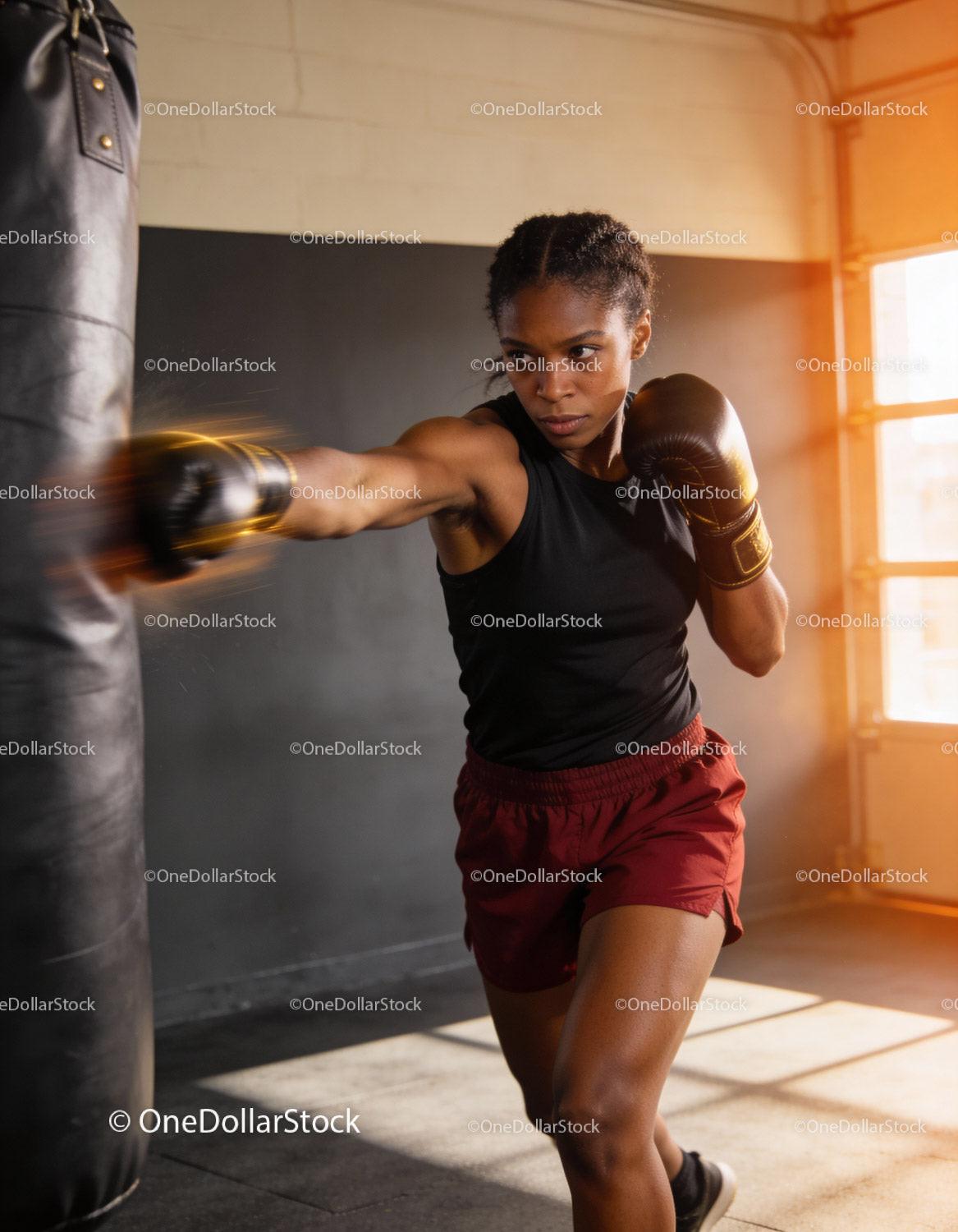 Focused female boxer training with punching bag indoors