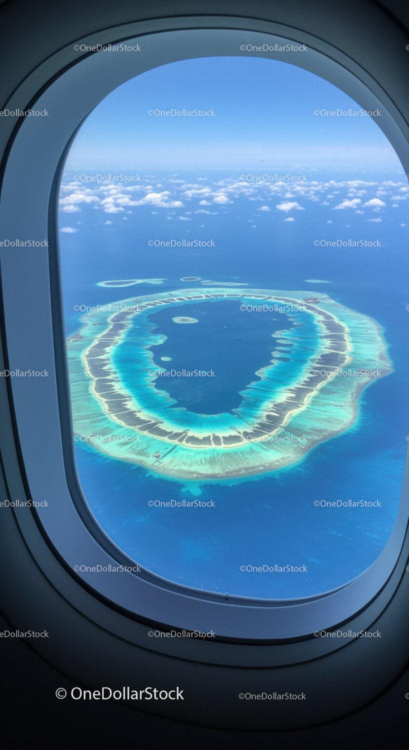 Aerial View of Tropical Island and Clear Blue Ocean From Airplane Window
