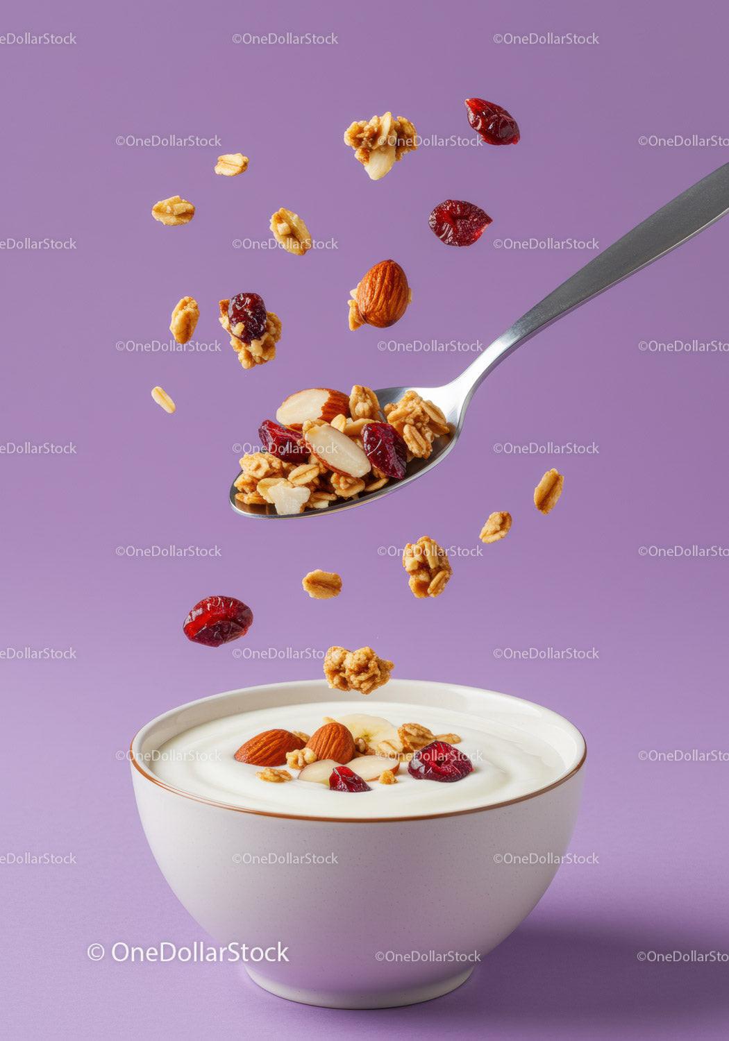 Granola and nuts falling into creamy yogurt bowl
