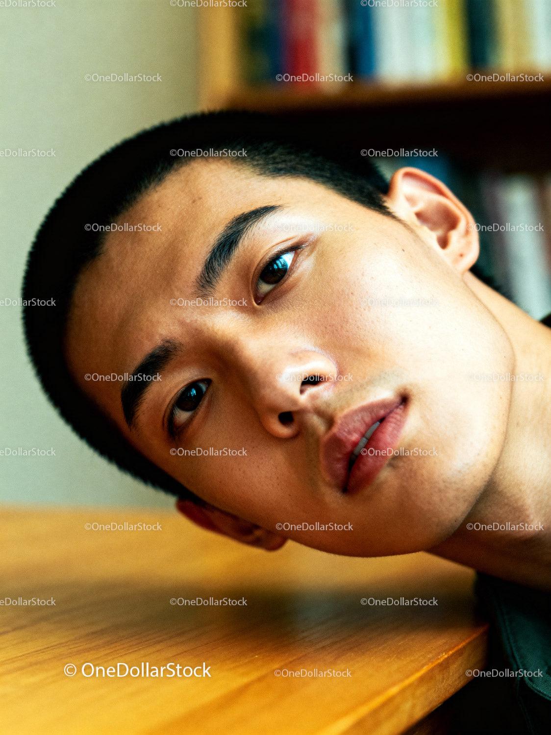 Young man resting face on wooden table indoors