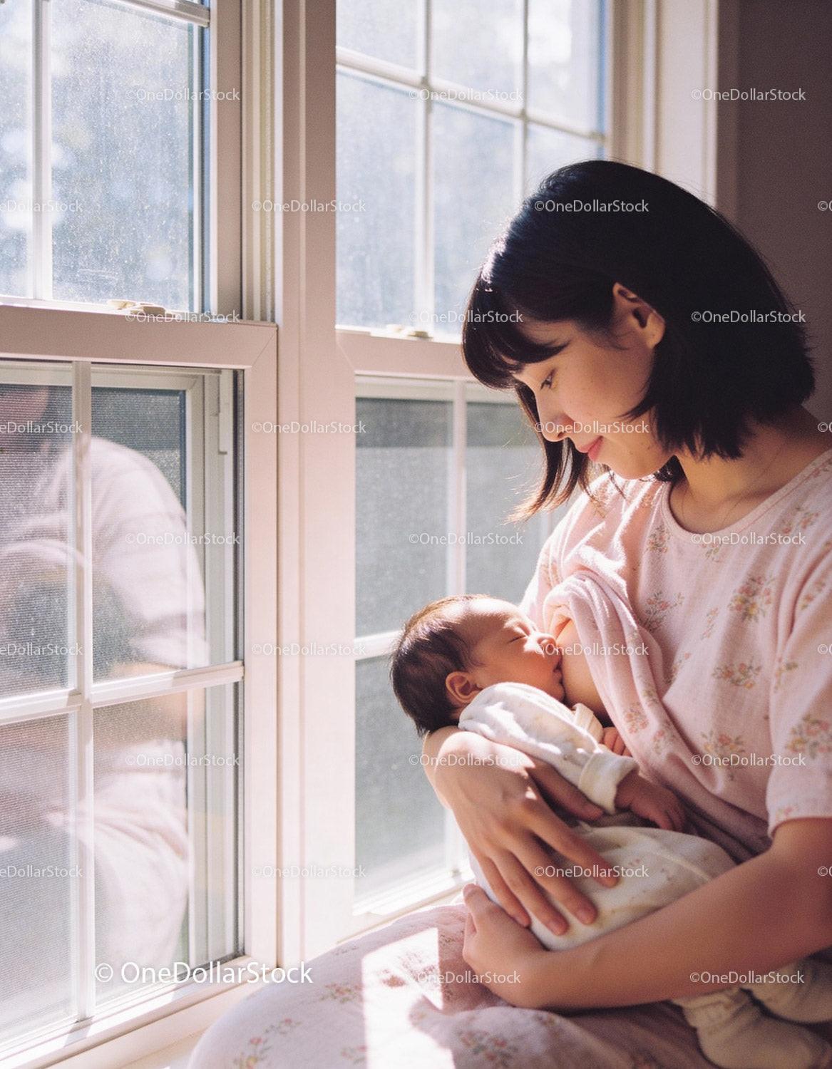 Mother tenderly breastfeeding newborn by sunlit window