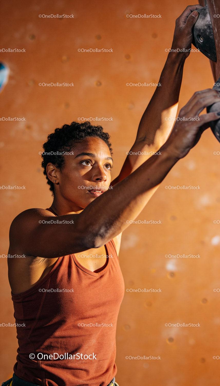 Focused young woman training on indoor climbing wall