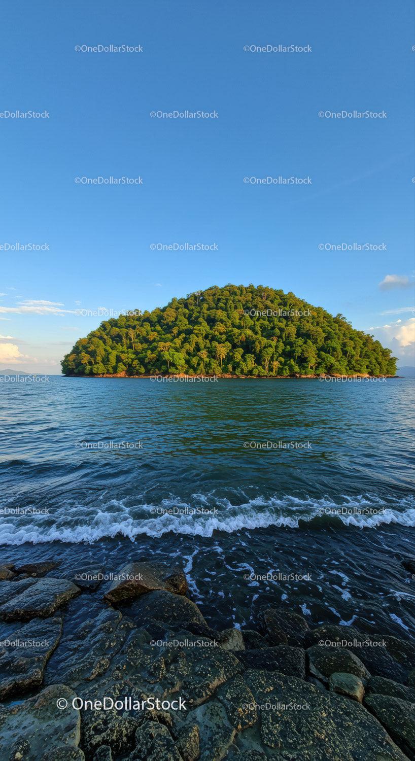 Tropical Green Island with Rocky Shoreline in Calm Blue Sea