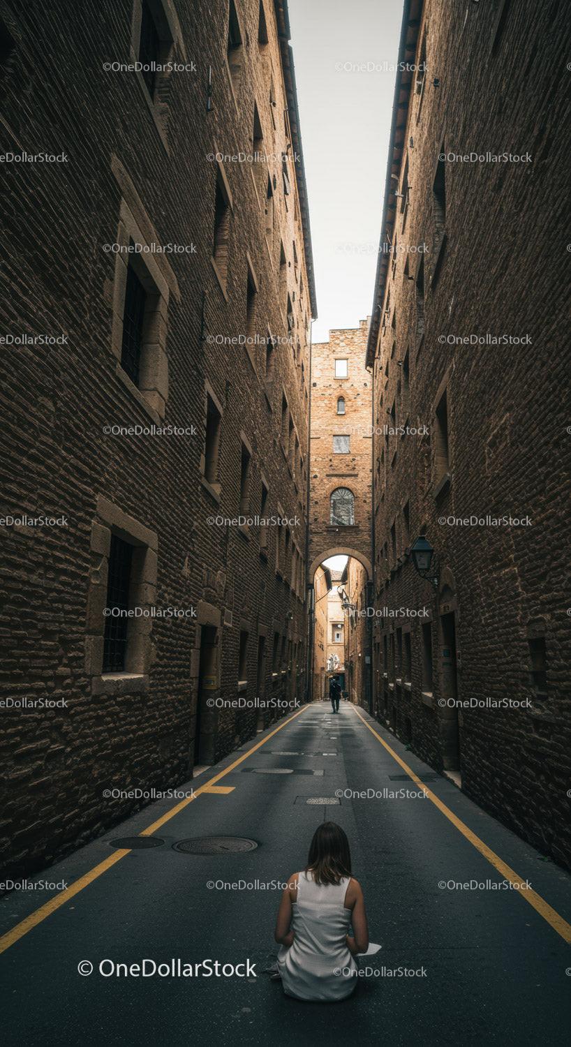 Woman in white dress sitting in narrow urban alleyway