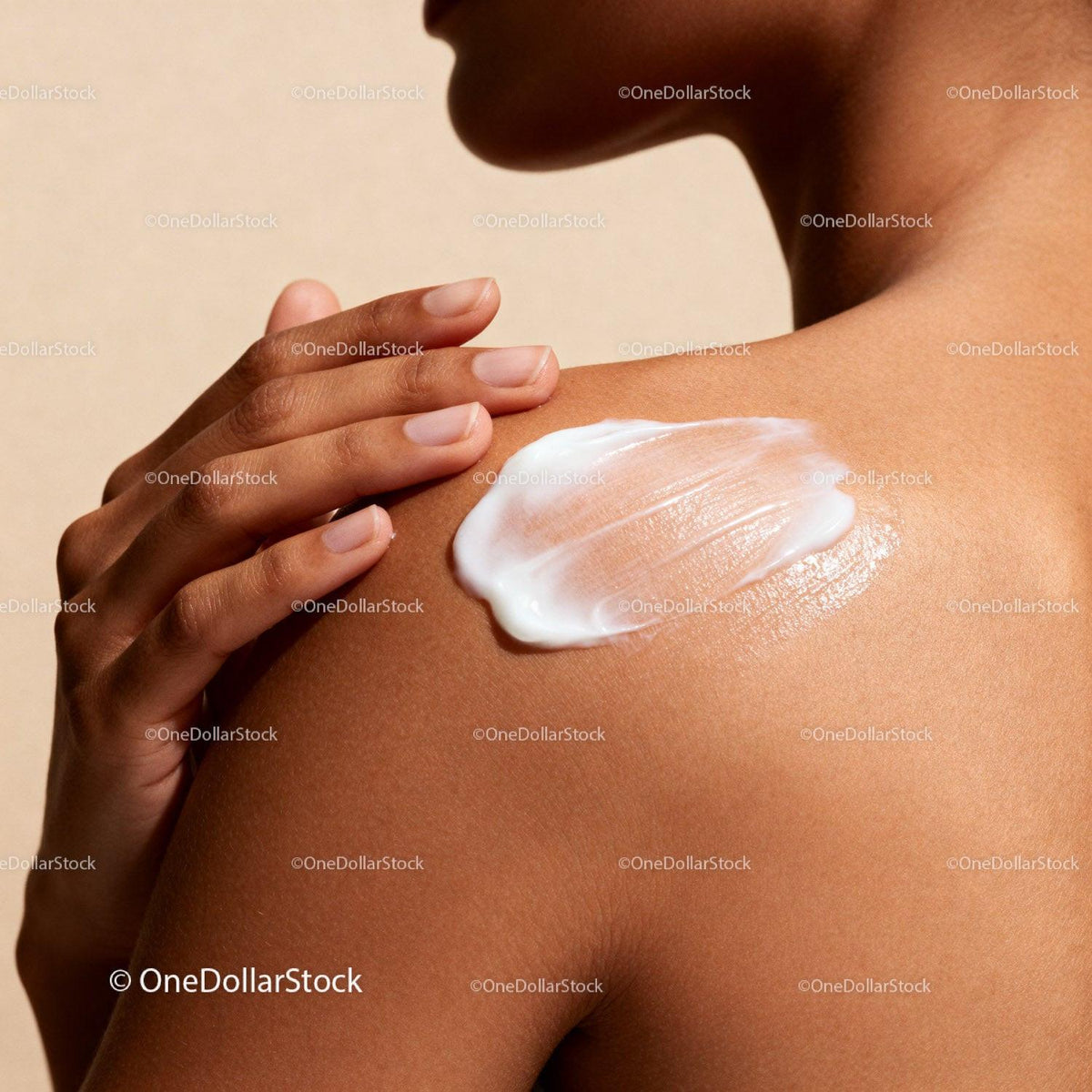 Close-up of woman applying cream on smooth shoulder