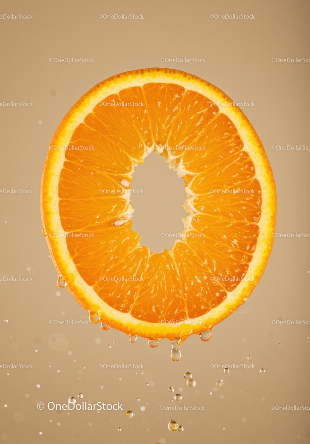 Fresh orange slice dripping with juice in beige background
