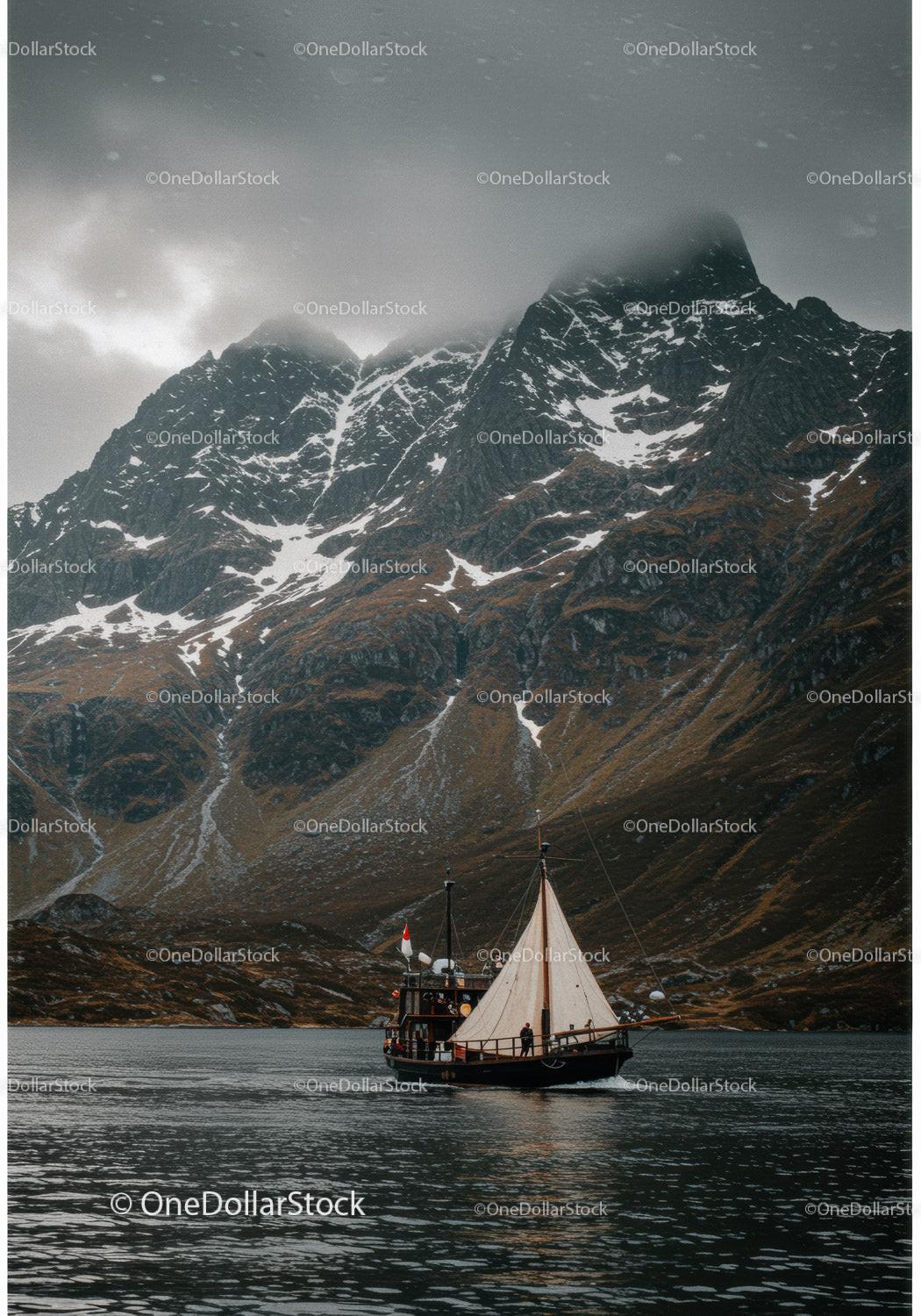Sailboat cruising near misty snow-capped mountains
