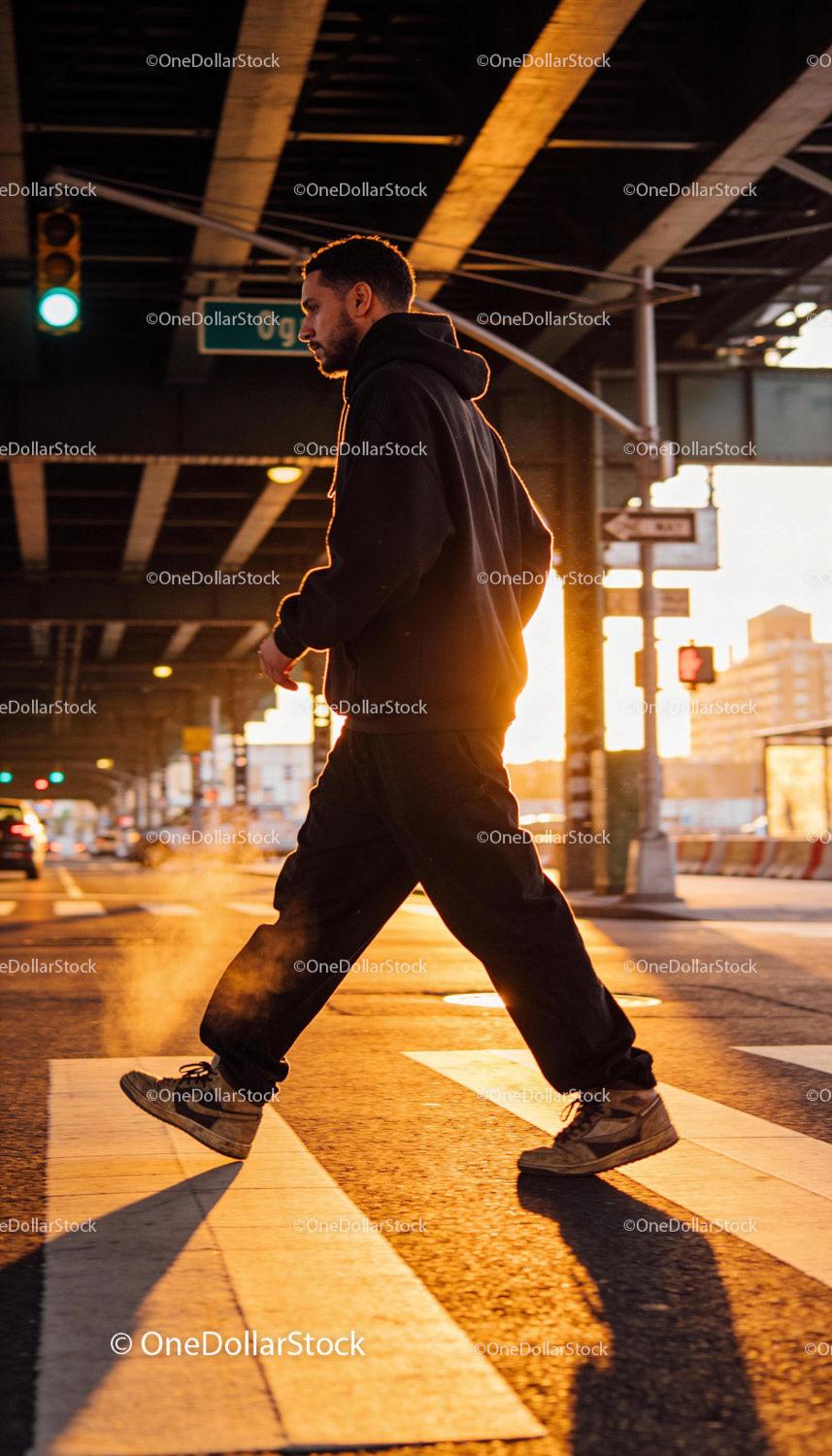 Man crossing street in urban hoodie during golden hour