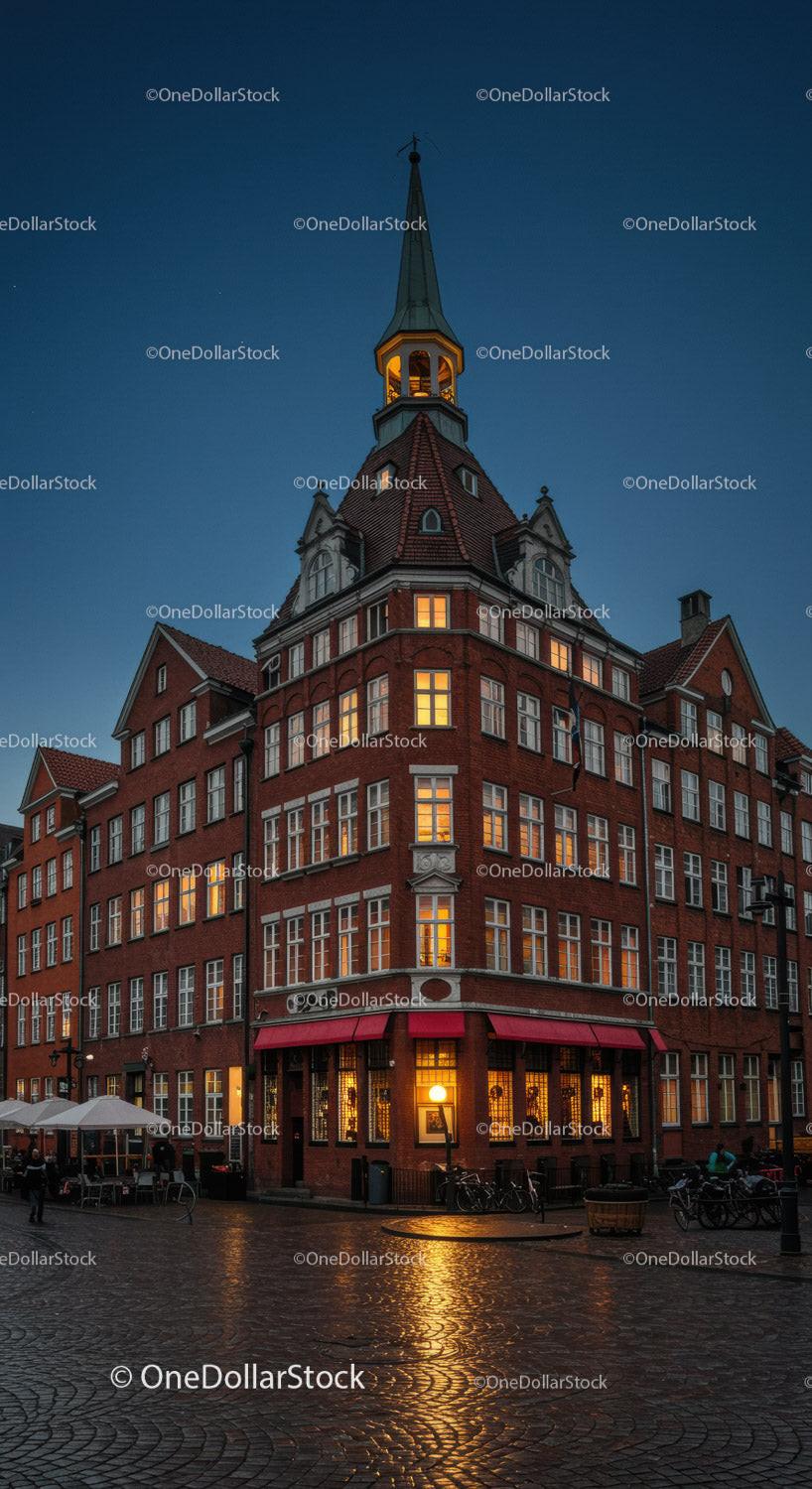 Historic Red Brick Building with Illuminated Windows and Spire at Night