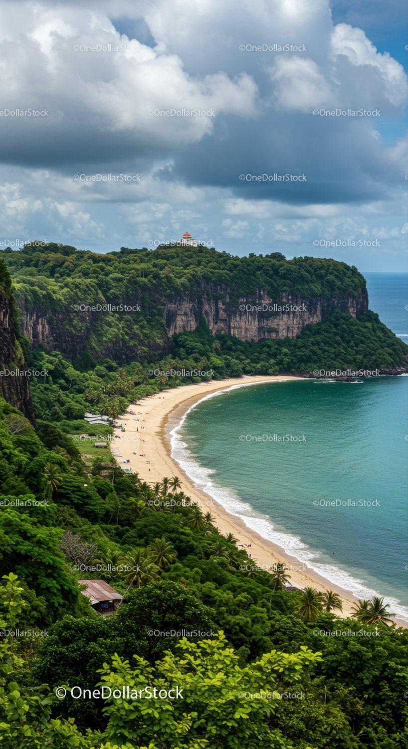 Lush Green Cliffs Overlooking Tropical Beach With Blue Ocean and Cloudy Sky