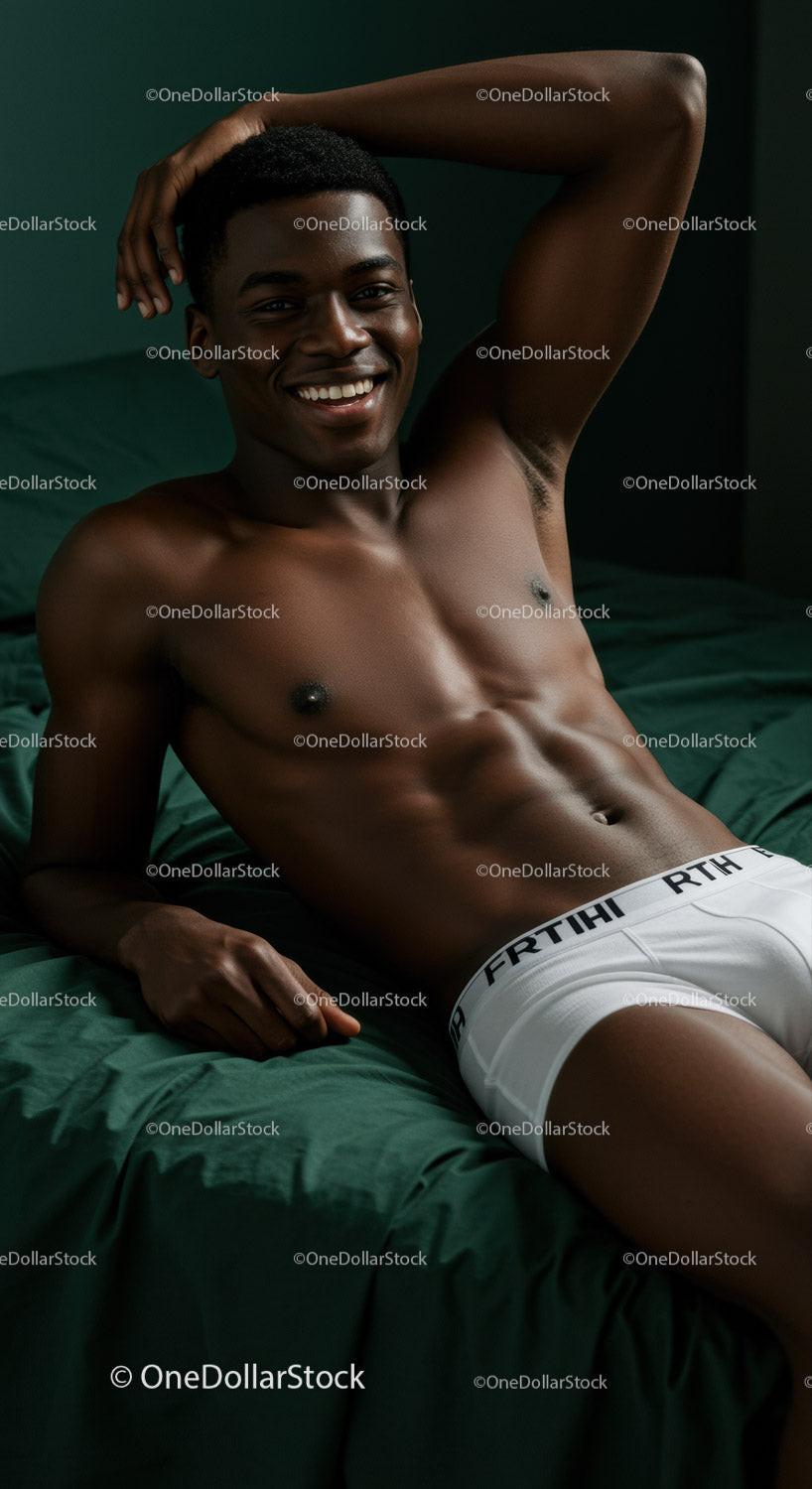 Smiling muscular man relaxing on dark green bed linens