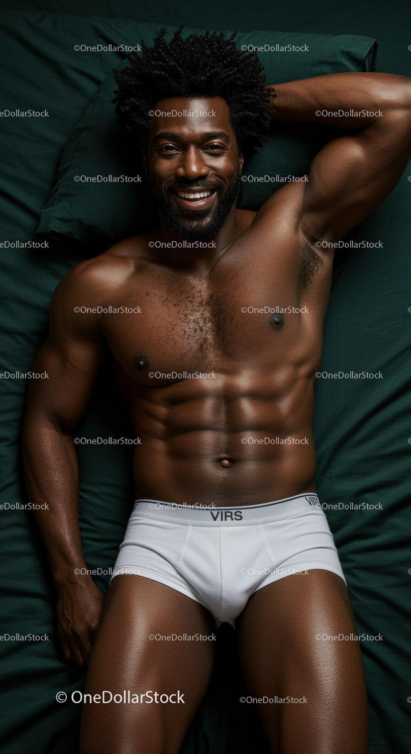 Smiling muscular man relaxing on dark green bed sheets