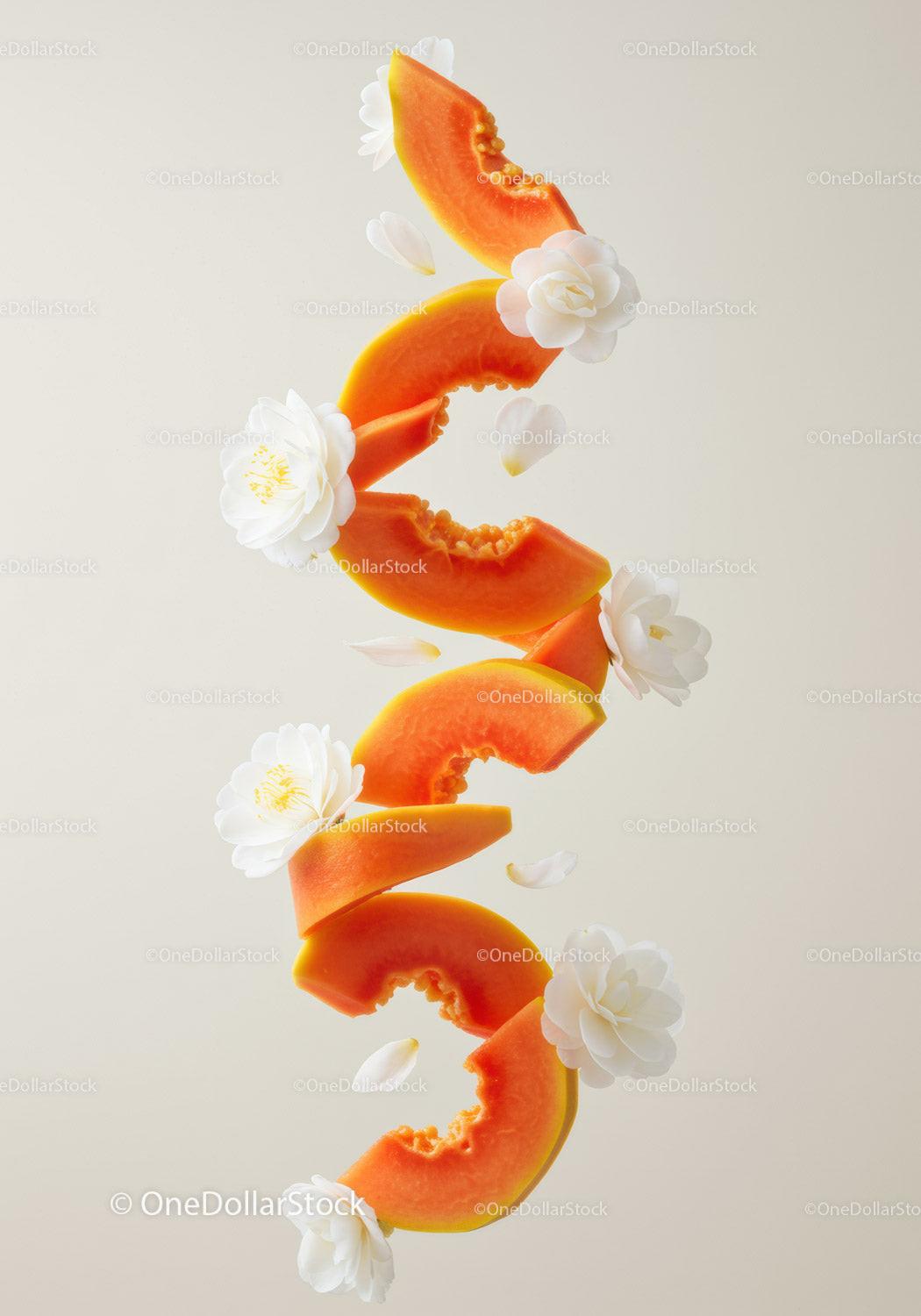 Fresh papaya slices with white camellia flowers floating
