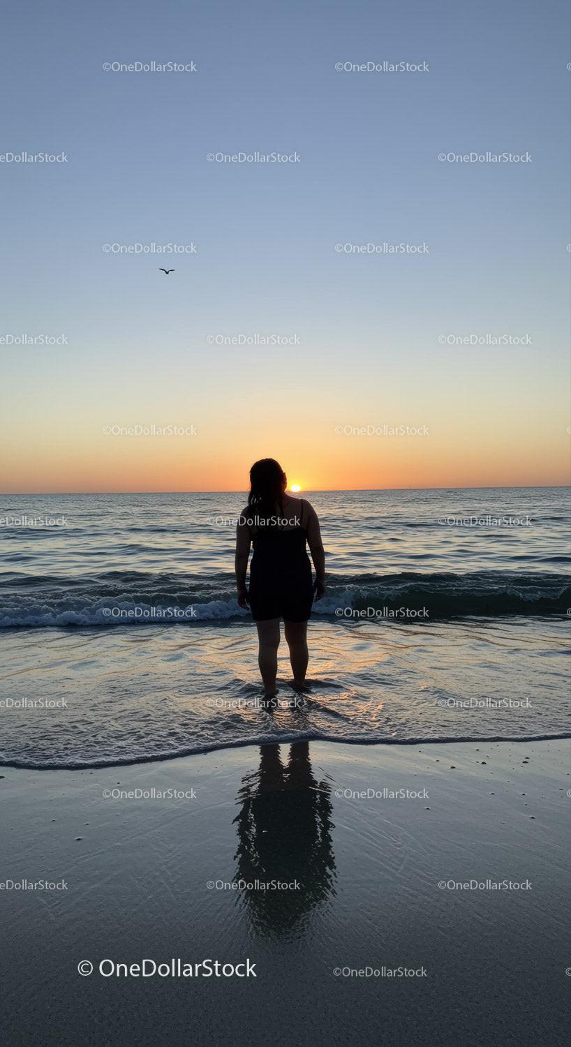 Silhouette of Woman Standing in Ocean During Sunset