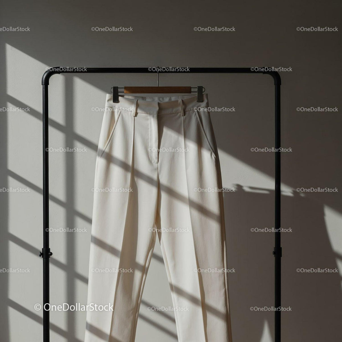 Elegant white trousers hanging on black rack JPG Mockup Image preview
